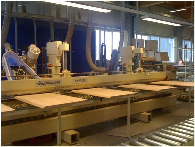 Industrial woodworking machine in a factory setting cutting wooden panels.