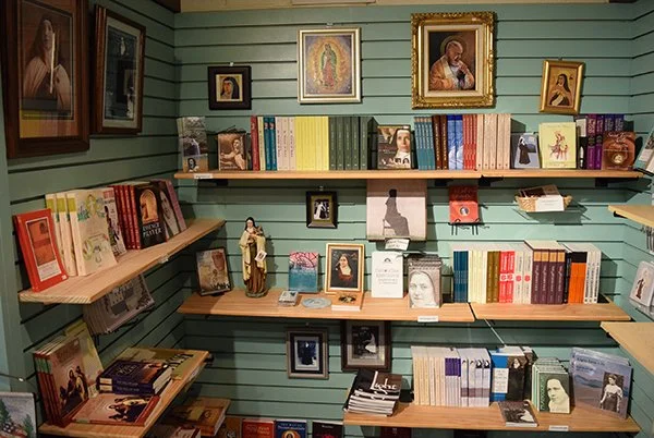 Bookshelves with religious and historical books, framed pictures, and small statues in a room with green panel walls.