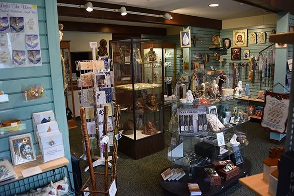 Interior of an antique shop with display cases and shelves filled with collectibles, figurines, jewelry, and decorative items.