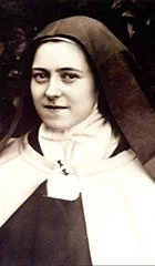 A young woman in a nun's habit with a solemn expression, facing the camera.