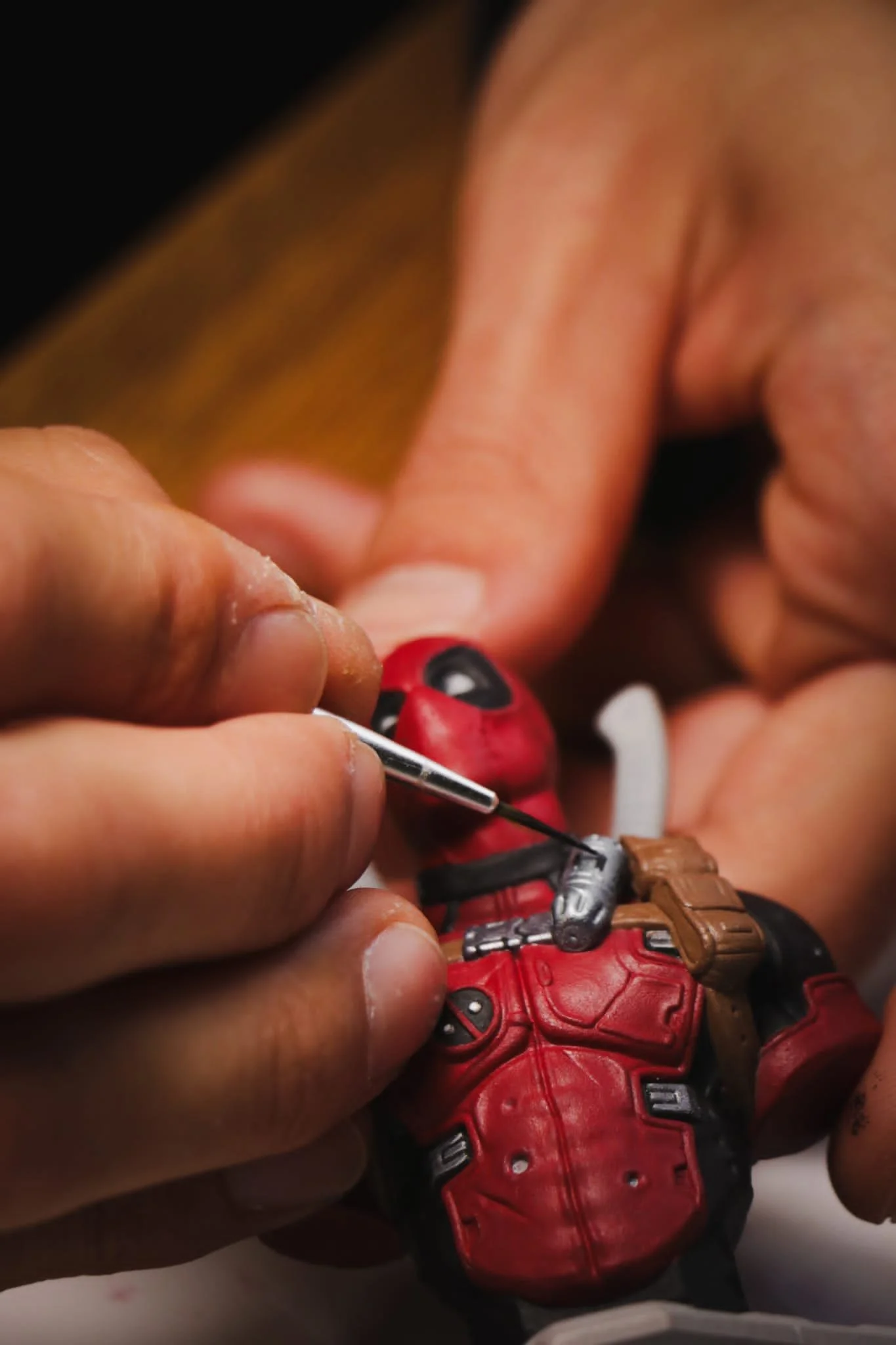 Pessoa pintando a figura do Deadpool com uma ferramenta de pintura.