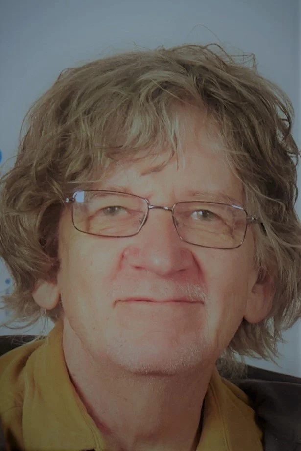 a headshot of john grey with a gray background