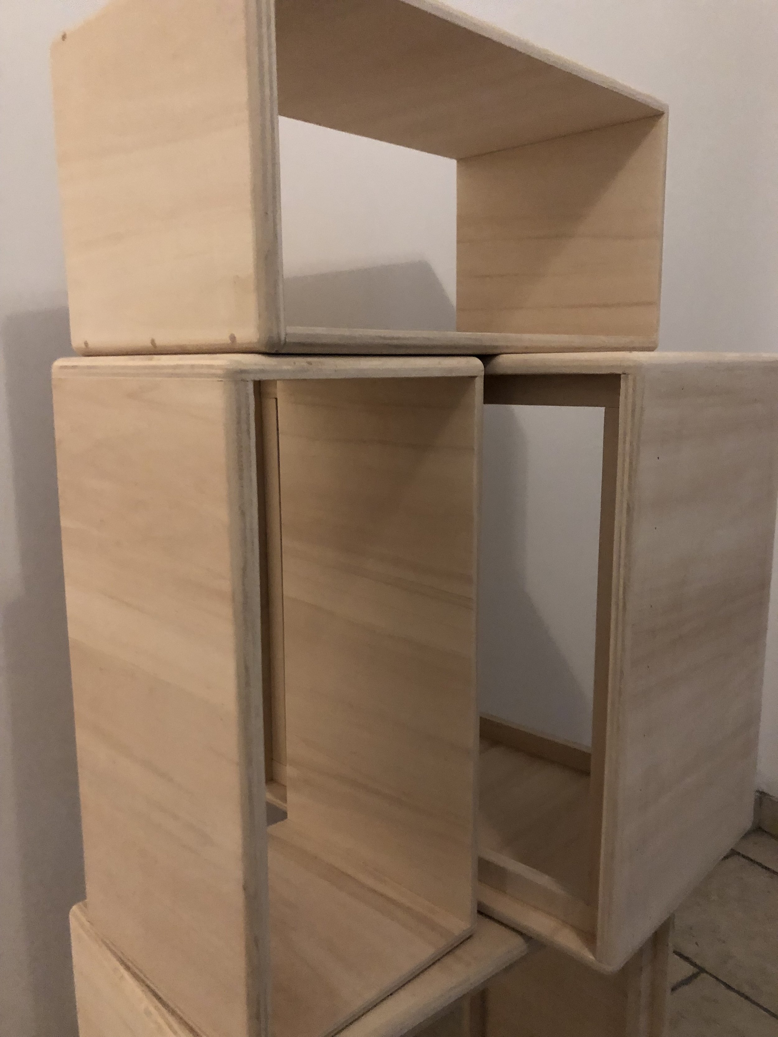 Un assemblage de boitiers d'amplificateurs en  contreplaqués, formant une structure cubique ouverte.