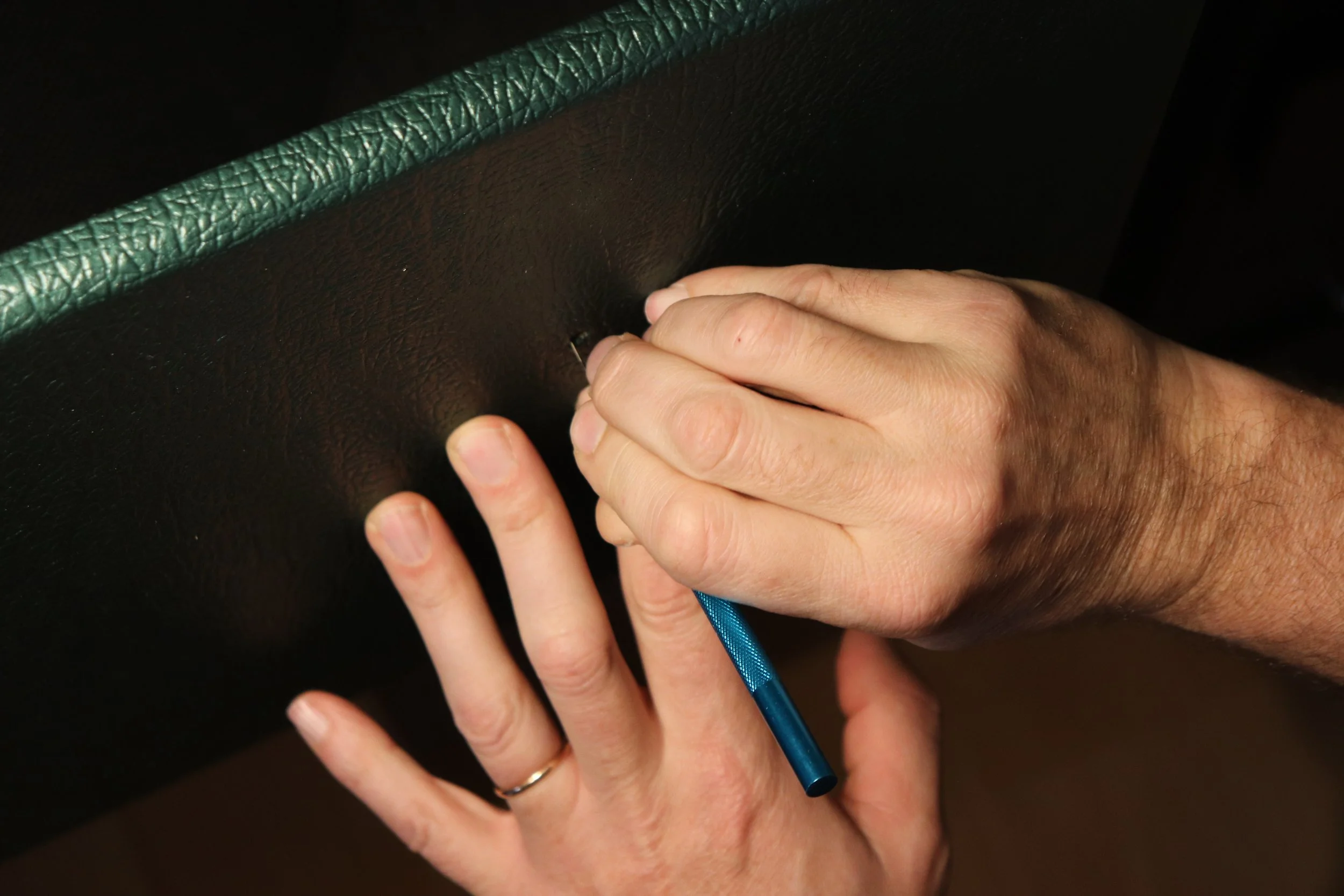 Une personne utilise un scalpel pour réaliser la finition d'un boitier d'amplificateur en  Tolex british racing green.
