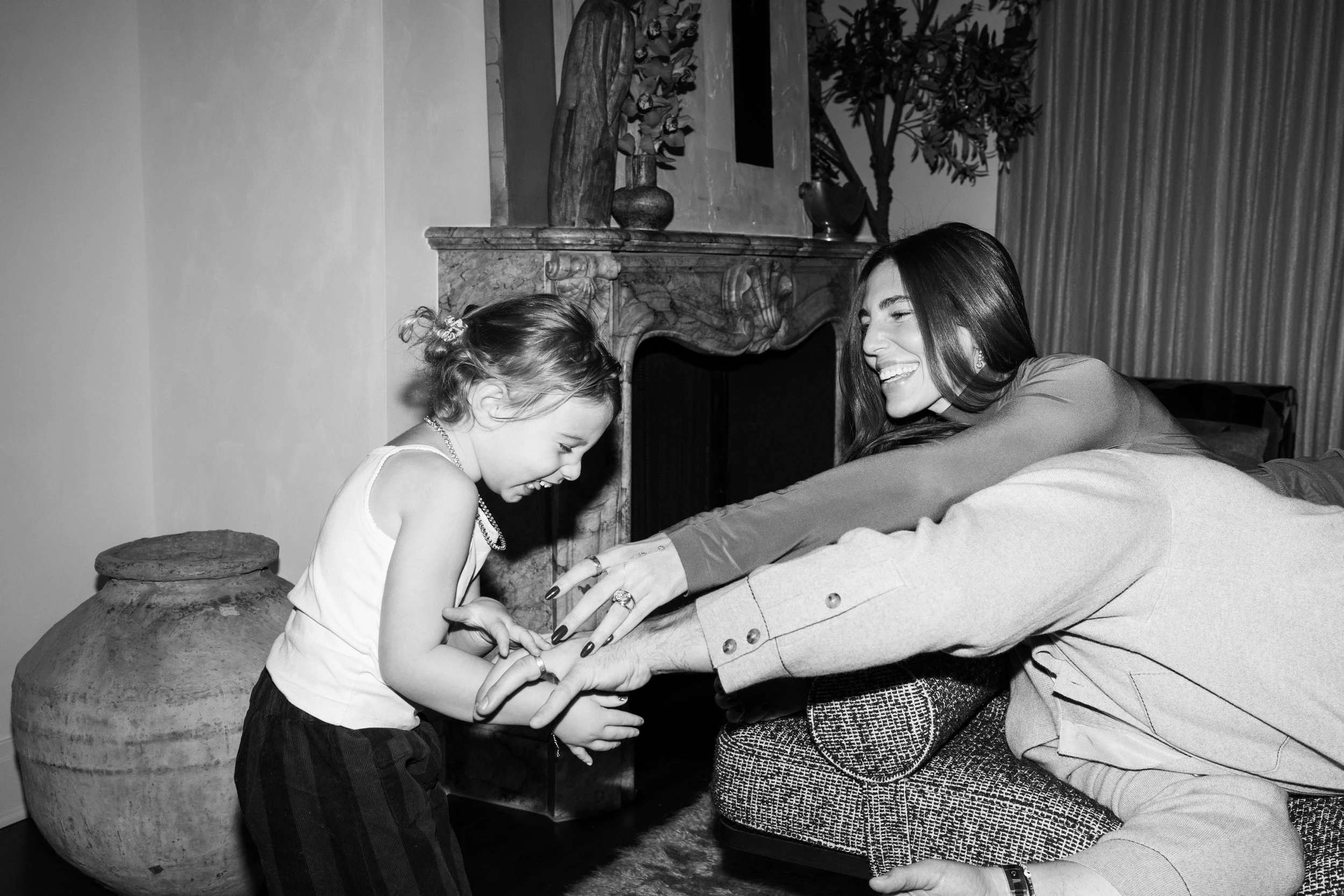A woman and a young girl playing a hand game together on a couch in a living room.