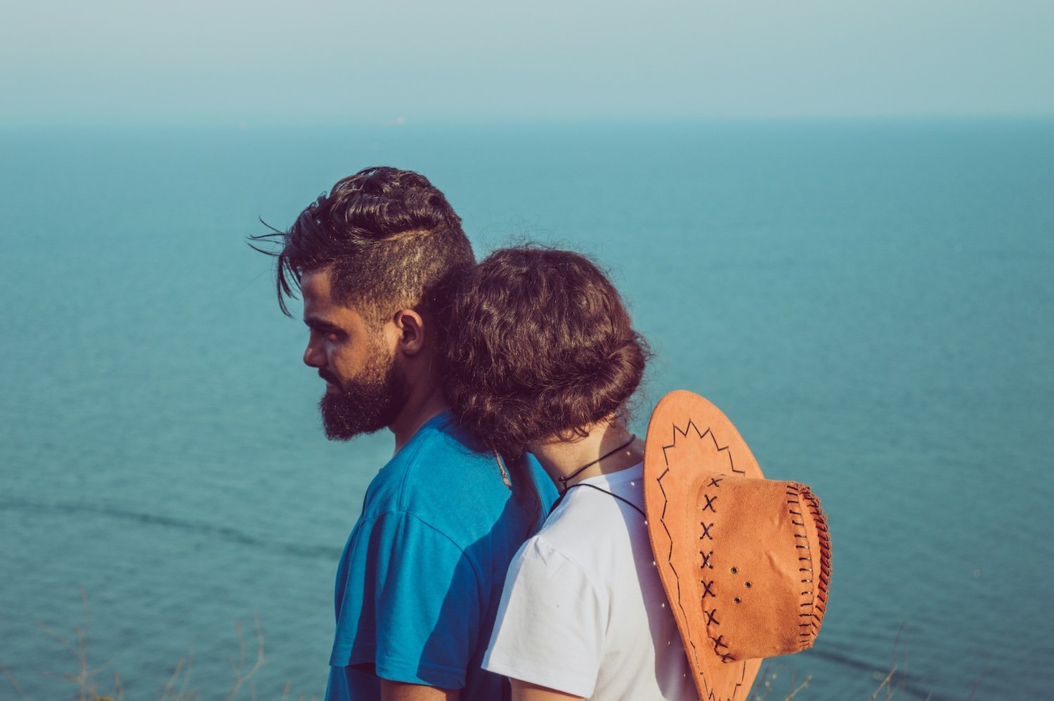 couple leaning on one another by ocean