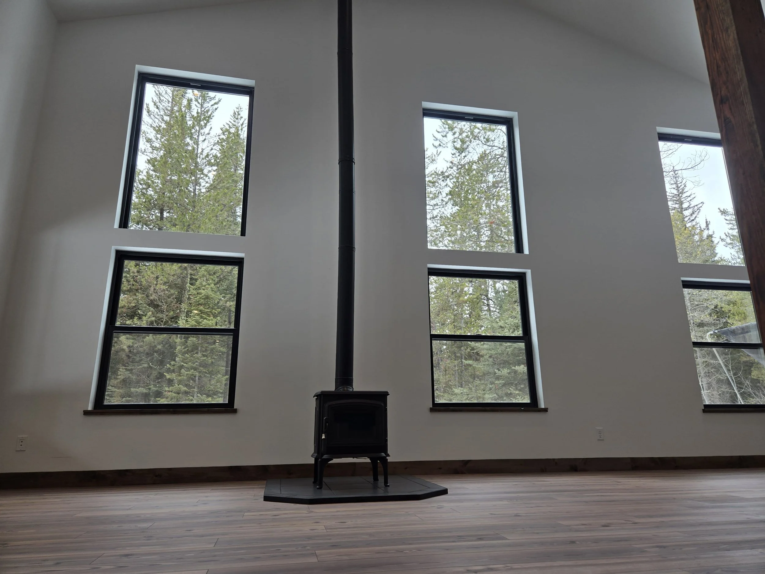 Image of a freestanding fireplace as the focal point in the room, positioned in between 4 large windows