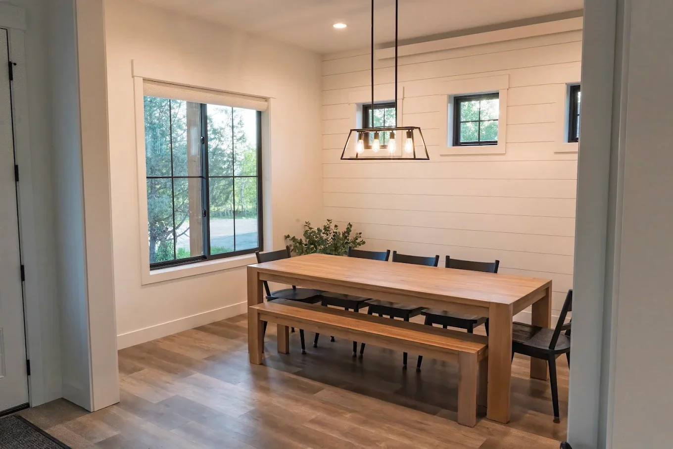 Dining room with a wooden table, black chairs, and a light fixture hanging above.