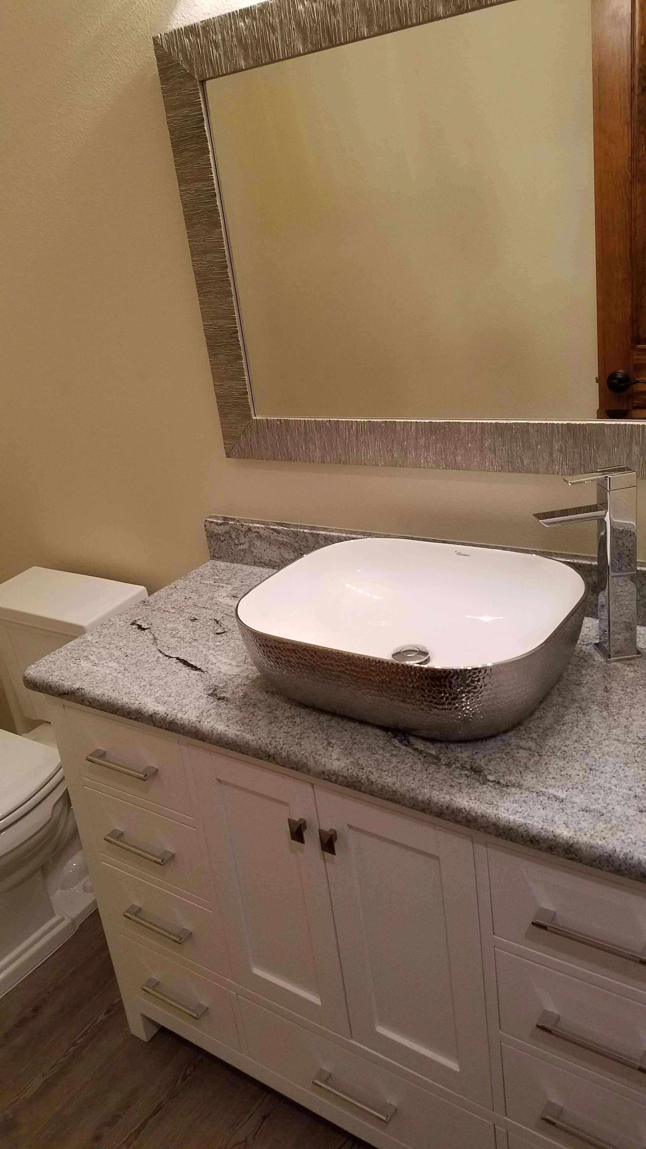 Bathroom with stone sit on top sink and countertop on top of a white vanity.