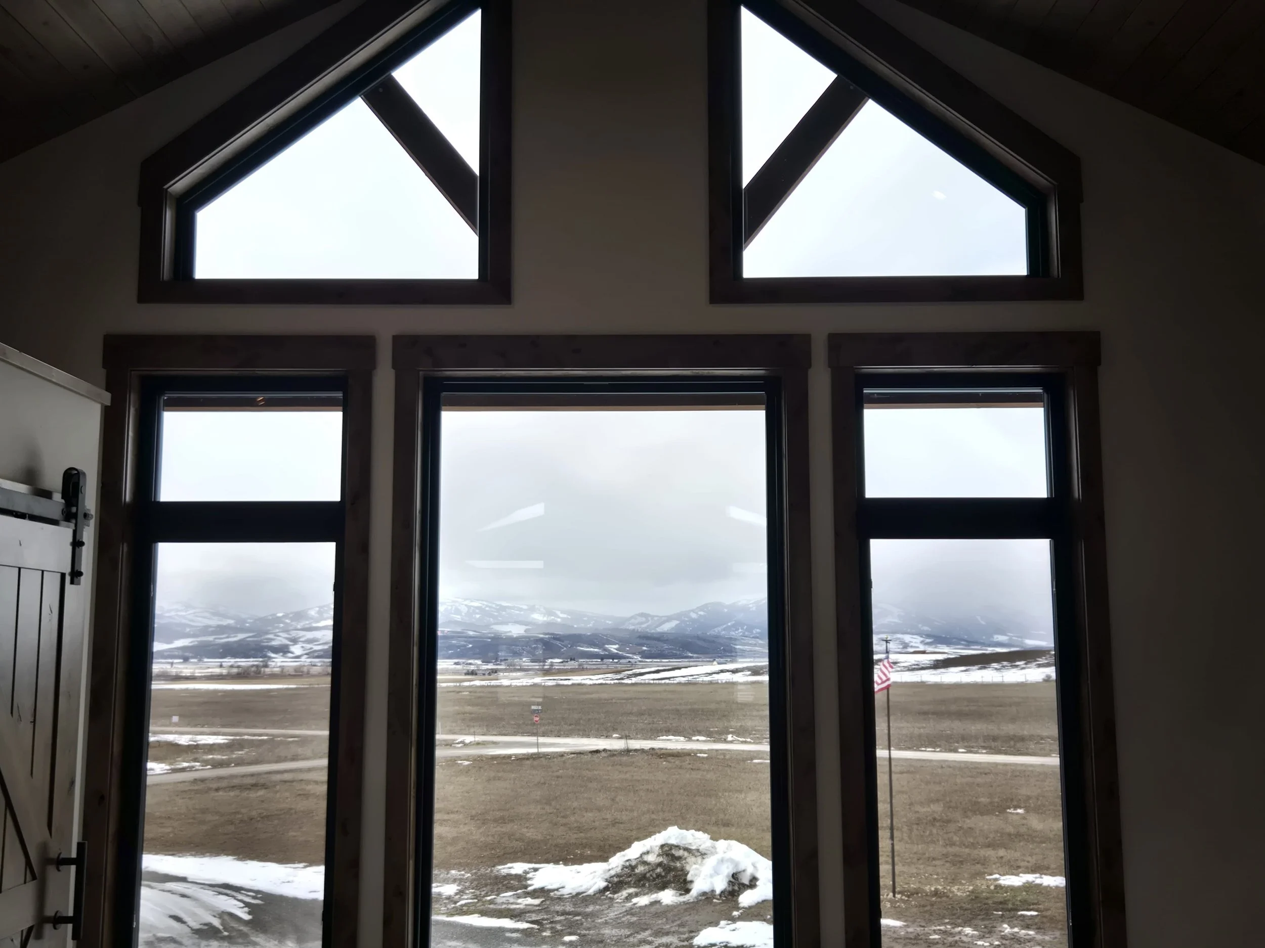 View through large windows showing a snowy mountain landscape with cloudy sky.