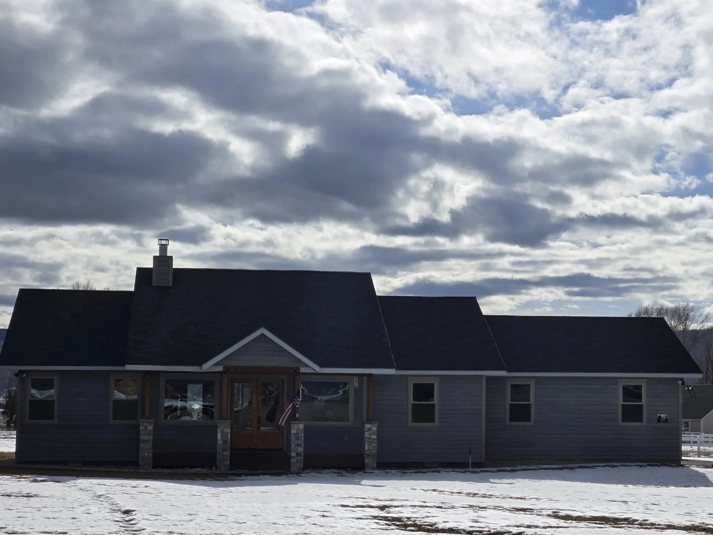 Outside view of a home located in Thayne Wyoming with an over cast sky and a snow yard.