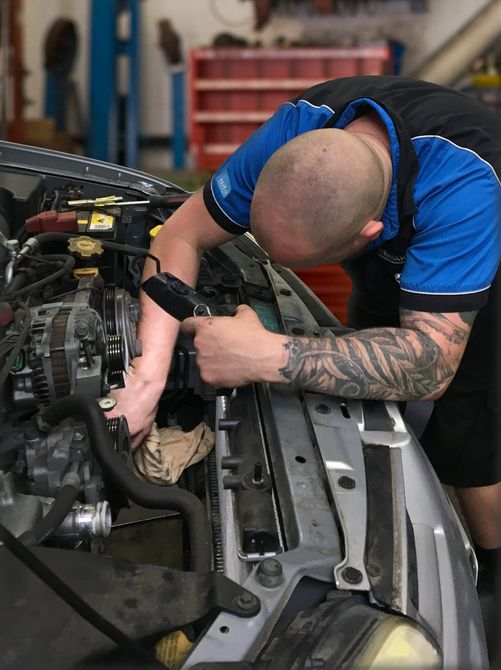 A mechanic working on a car engine in a garage.