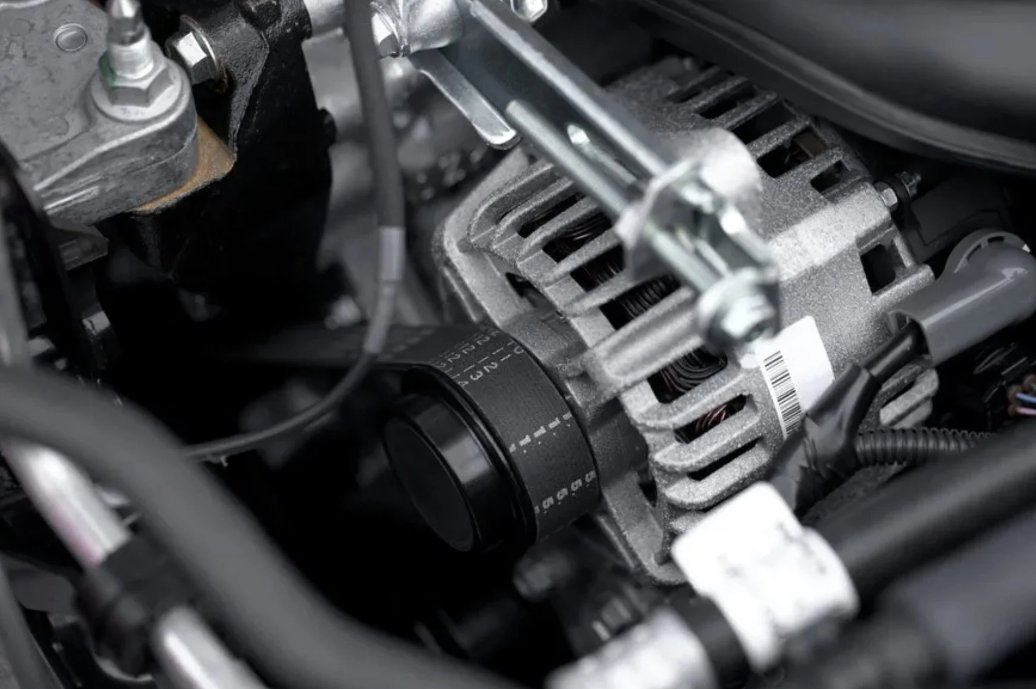 Close-up of an automotive alternator installed in a vehicle engine.