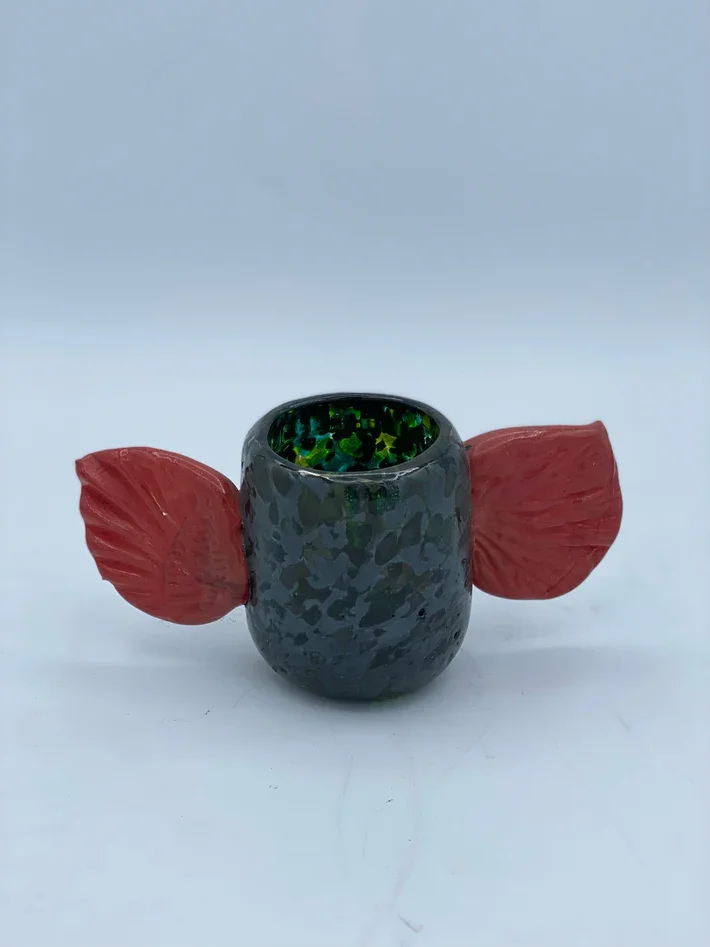 A decorative glass piece resembling an animal with black textured body, red ears, and a green marbled interior.