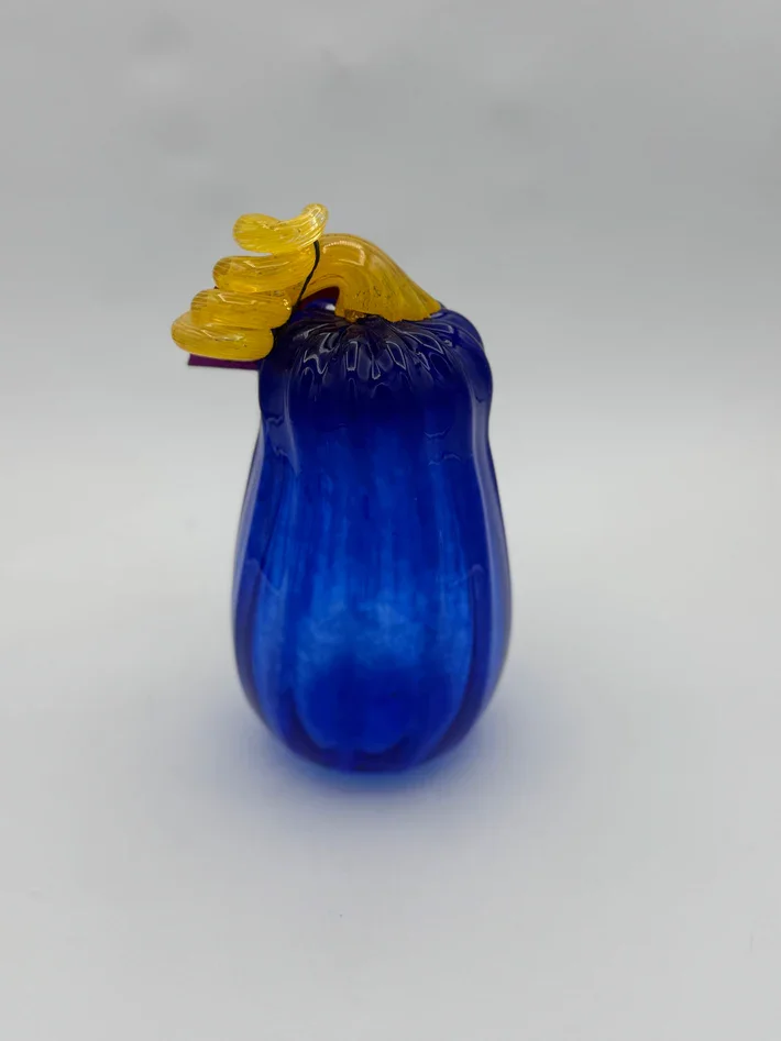 Colorful glass sculpture resembling a blue vase with yellow glass decoration on top.