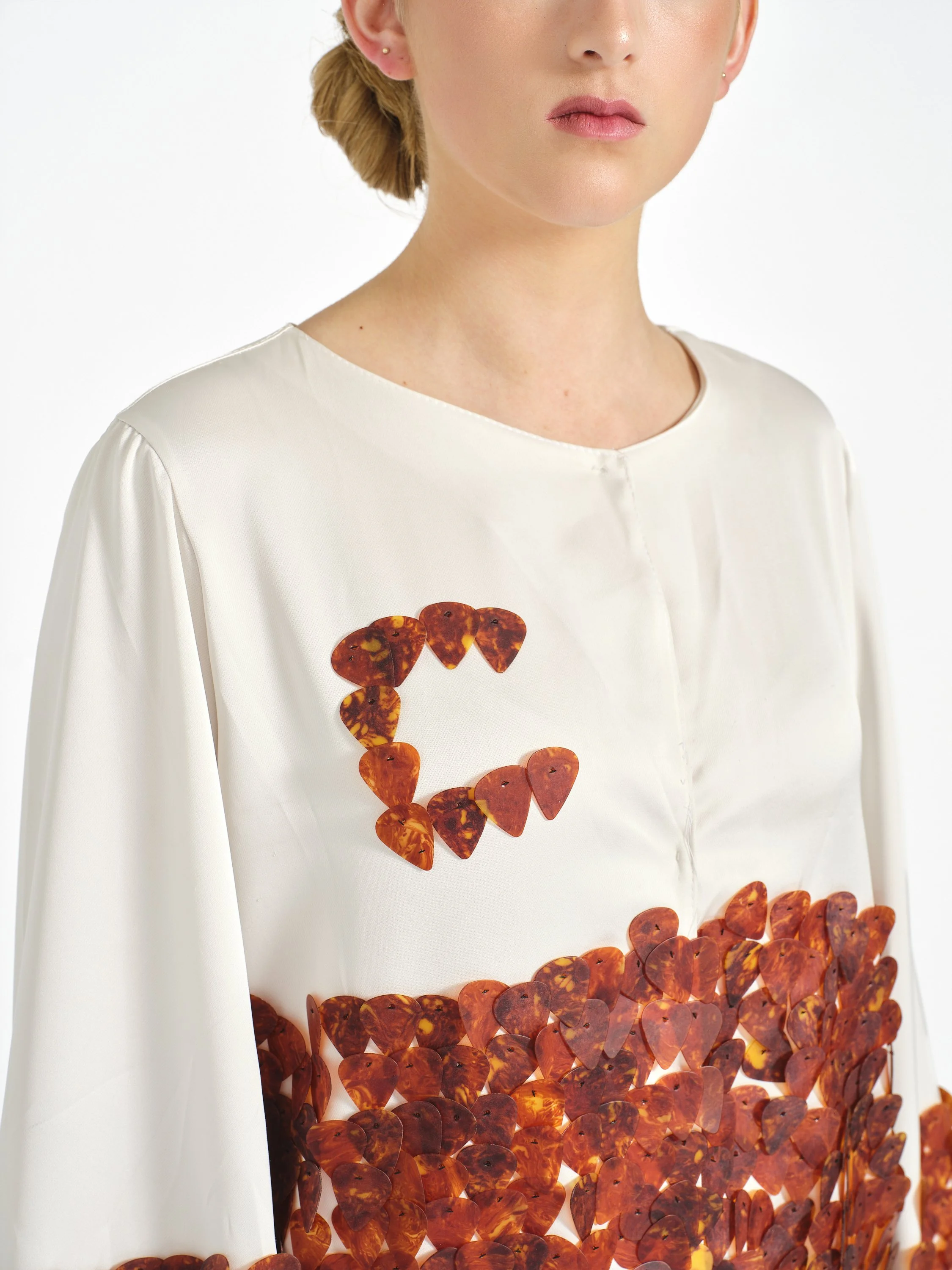 Close-up of a woman wearing a white blouse decorated with an orange tortoiseshell heart pattern