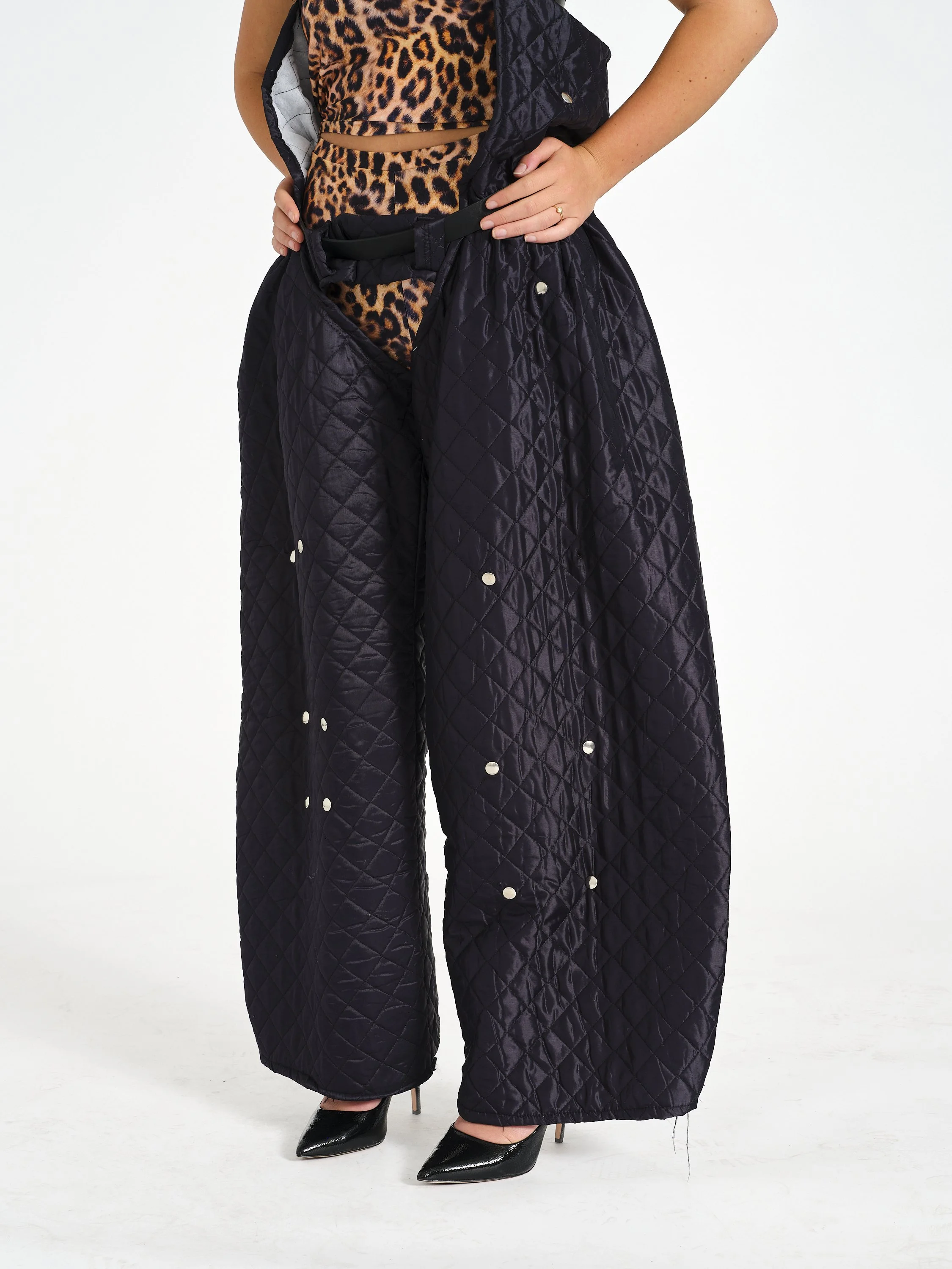 Cropped fashion photo of a woman wearing a leopard-print top with black quilted wide-leg pants and pointed-toe heels.