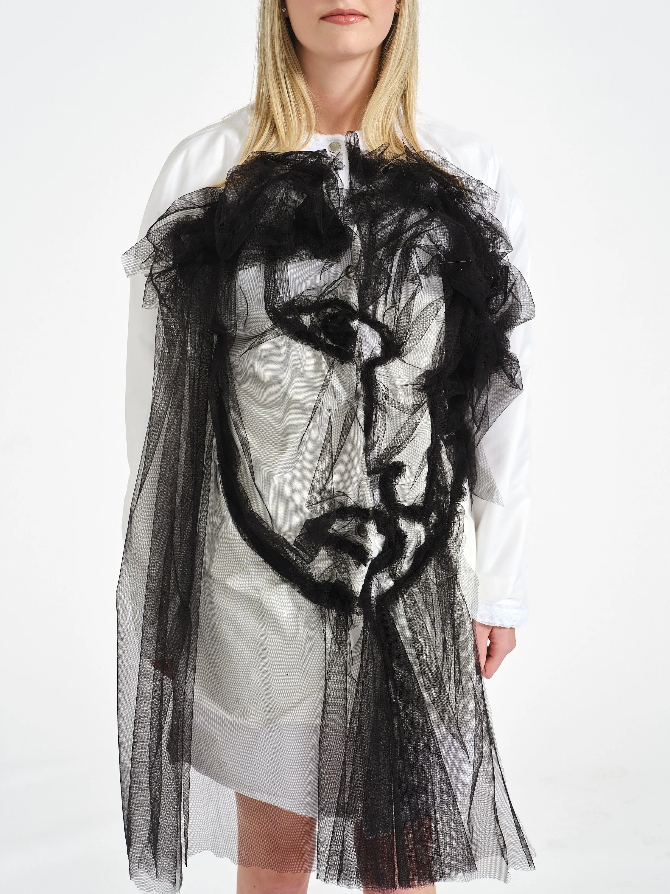 Woman wearing a white dress with dramatic black tulle ruffles and sheer overlay