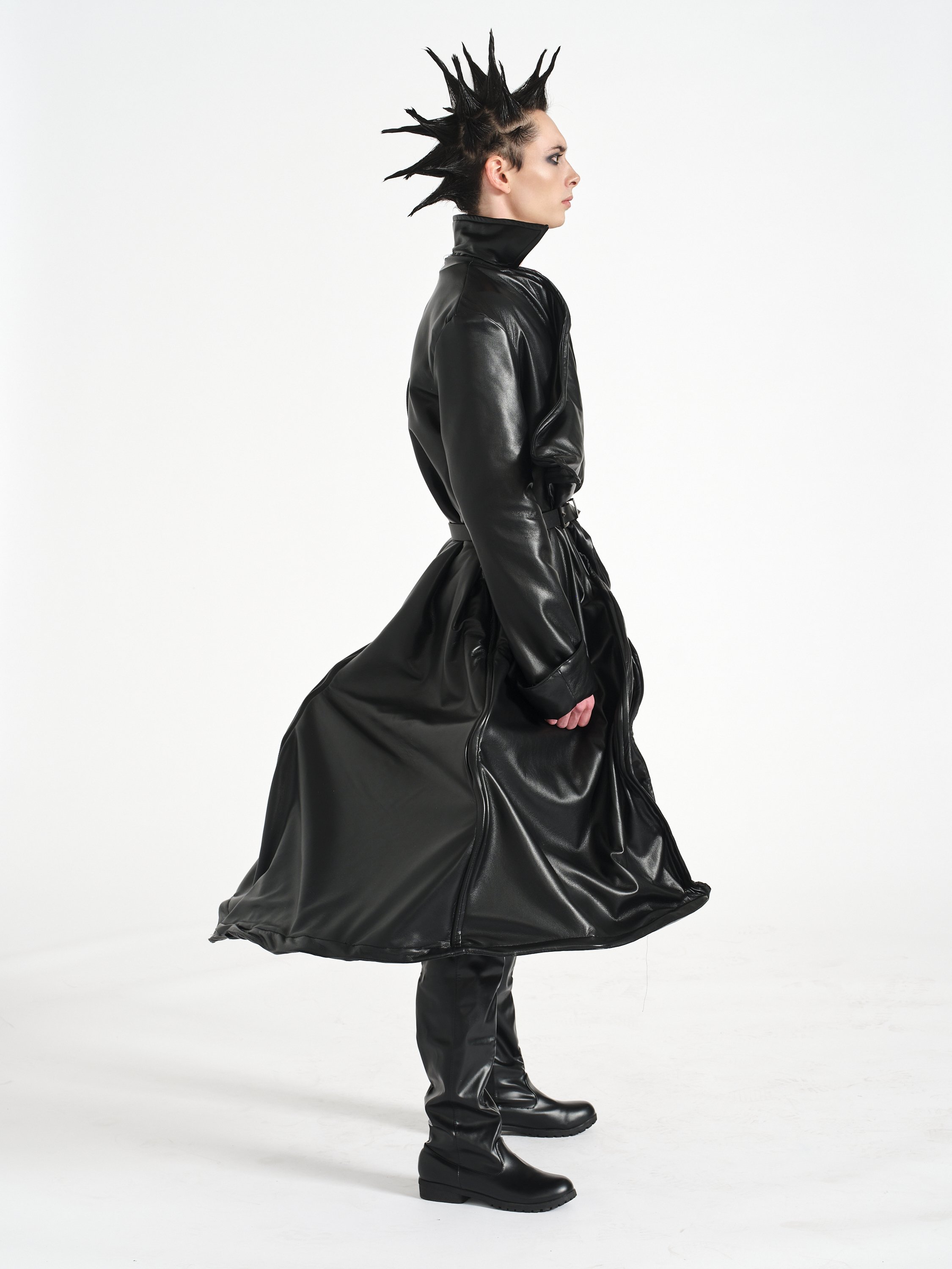 Fashion model in a black leather trench coat, platform boots, dramatic spiked hairstyle, and dark eye makeup