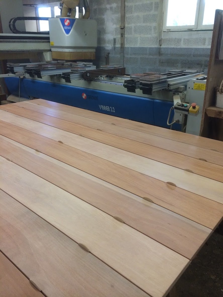 Une machine à travailler le bois dans un atelier, avec des planches de bois posées en avant.