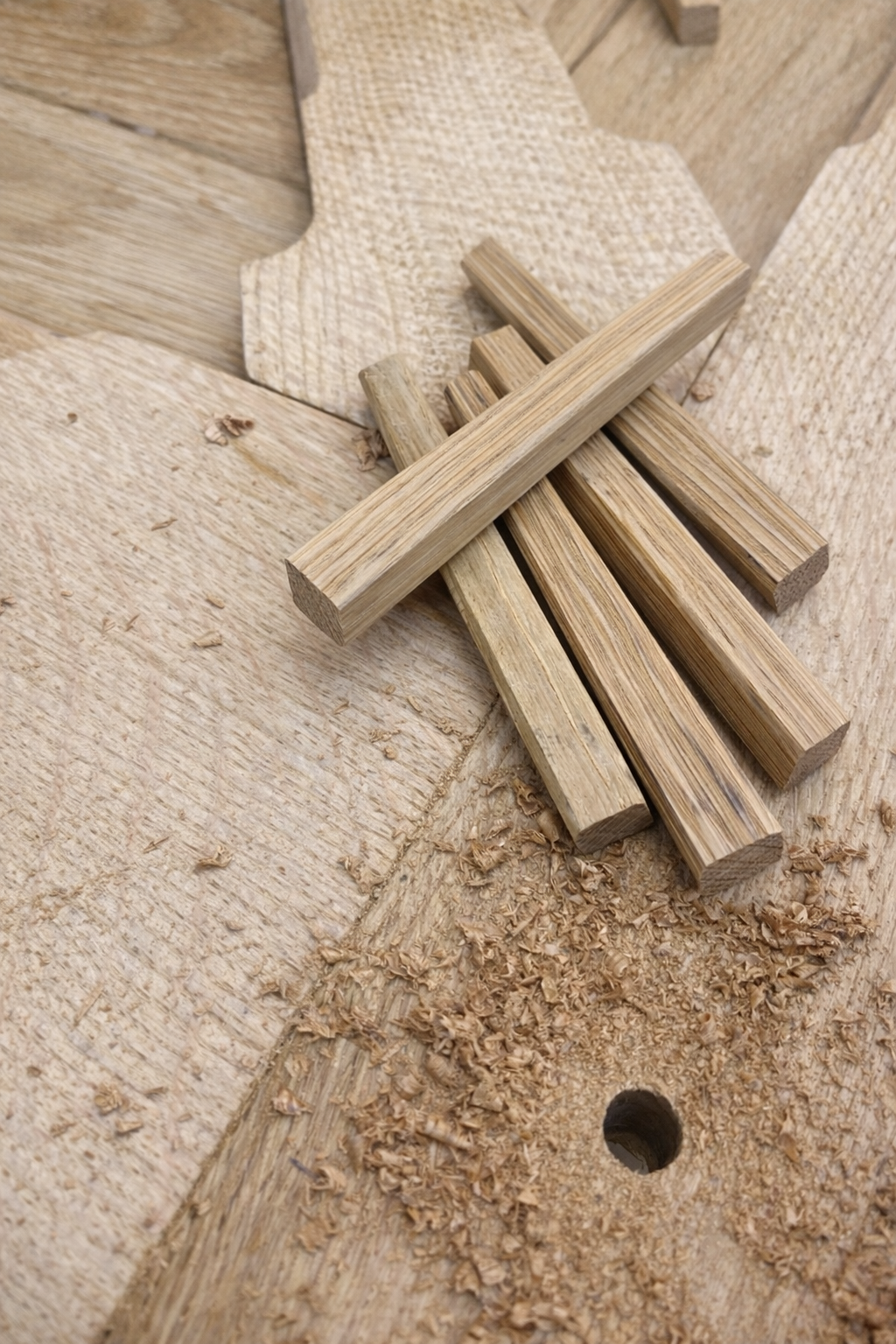Morceaux de bois et copeaux de bois sur une surface en bois, probablement une table de travail ou un établi de menuiserie.