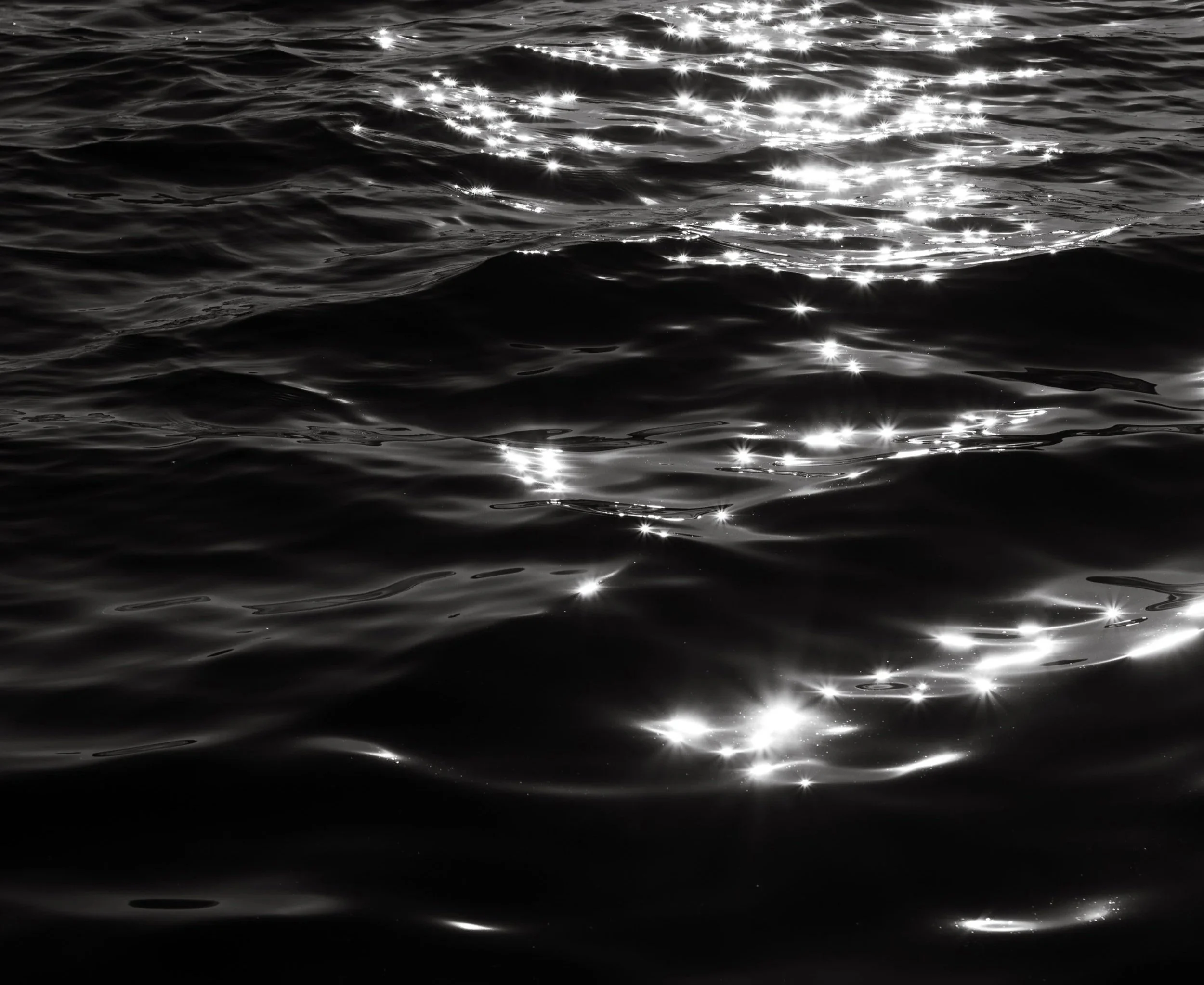Shiny reflections on the surface of dark water or ocean waves.