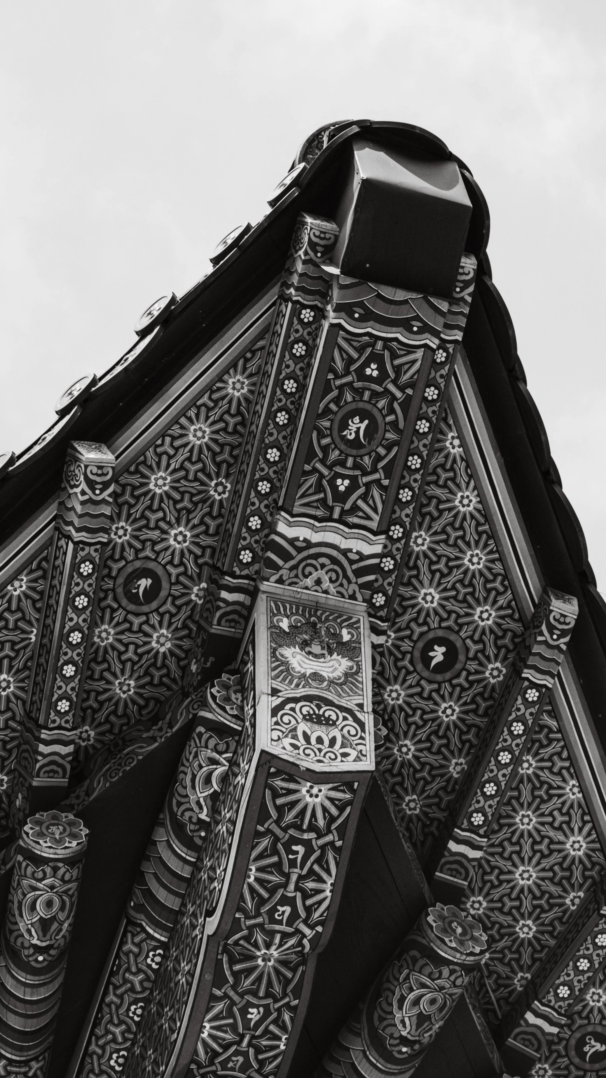 Close-up of the ornate, decorated underside of a traditional Asian Buddhist temple roof, with intricate patterns and symbols in black and white.