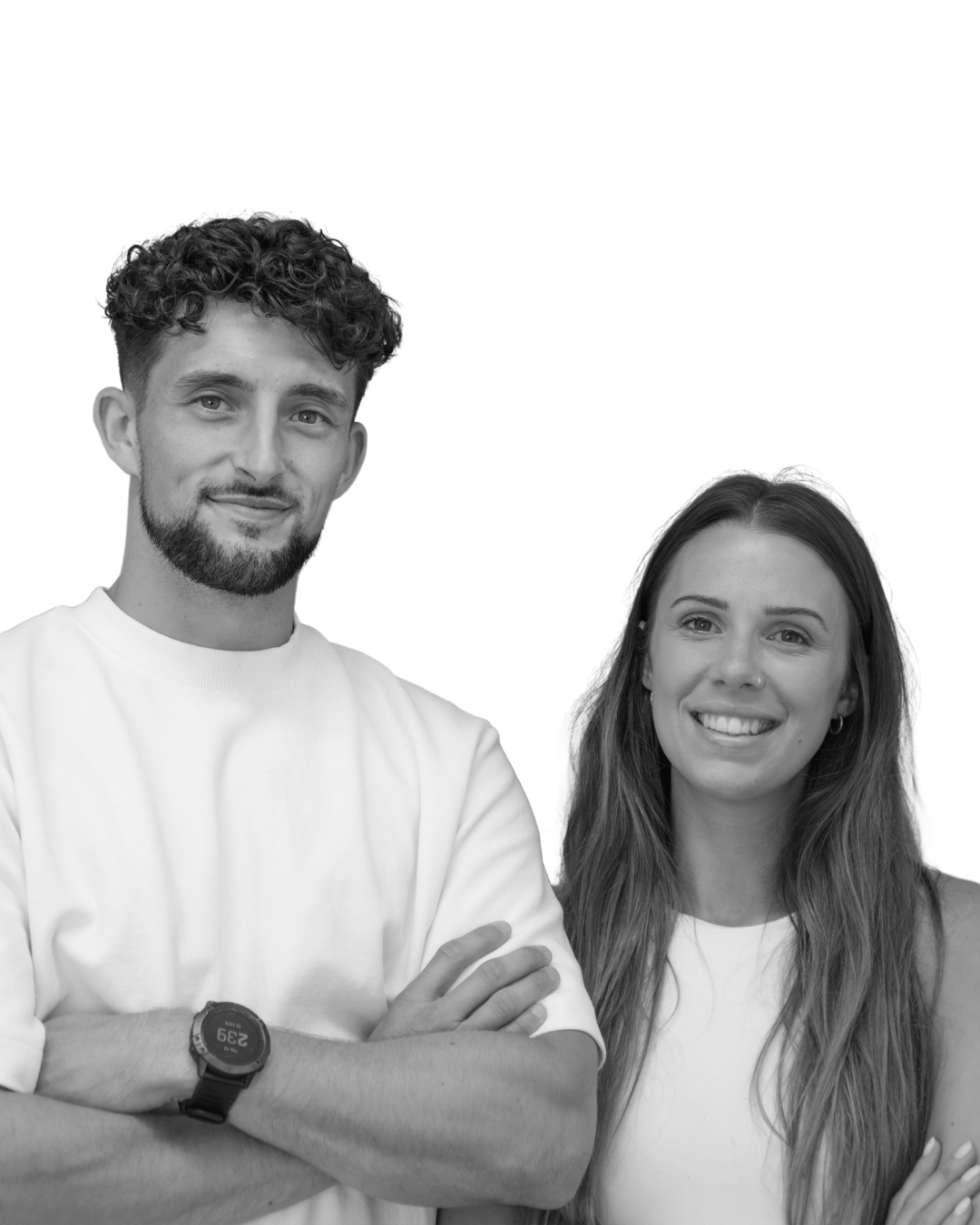 Black and white photo of a young man with curly hair and a beard, wearing a white t-shirt and a watch, smiling with arms crossed, standing next to a young woman with long hair and a nose piercing, smiling and wearing a sleeveless top.