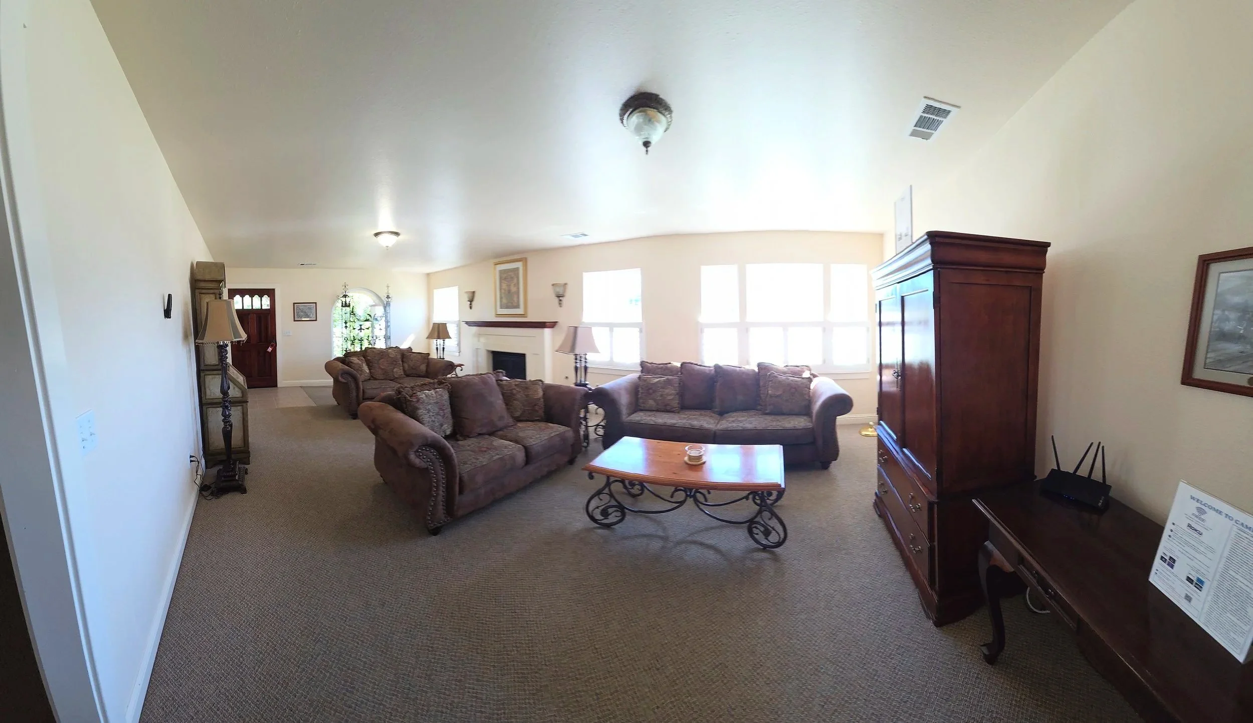 Living room with brown sofas, a coffee table, a fireplace, wooden cabinets, and windows letting in natural light.