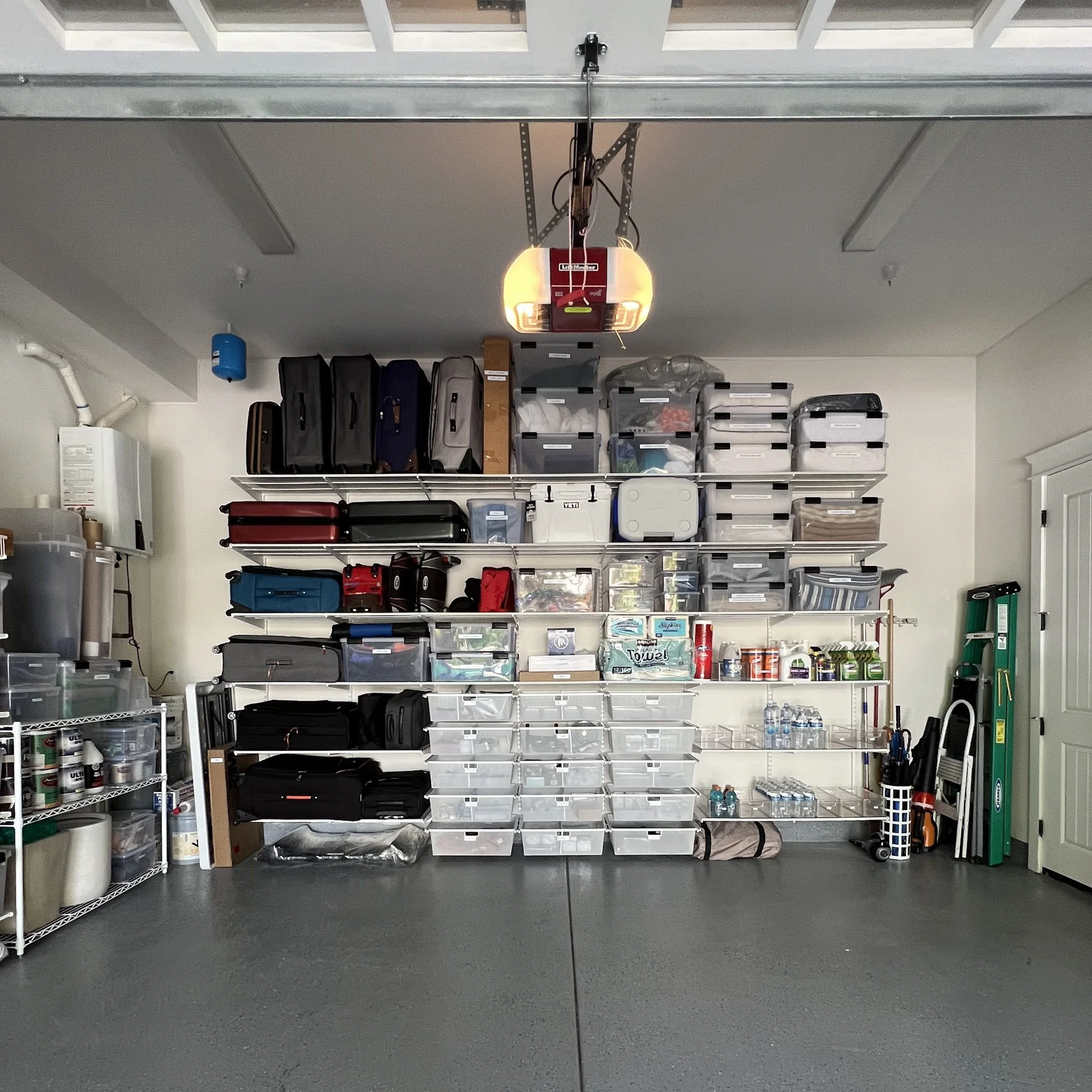 Garage with organized shelves containing storage bins, boxes, and various household items.