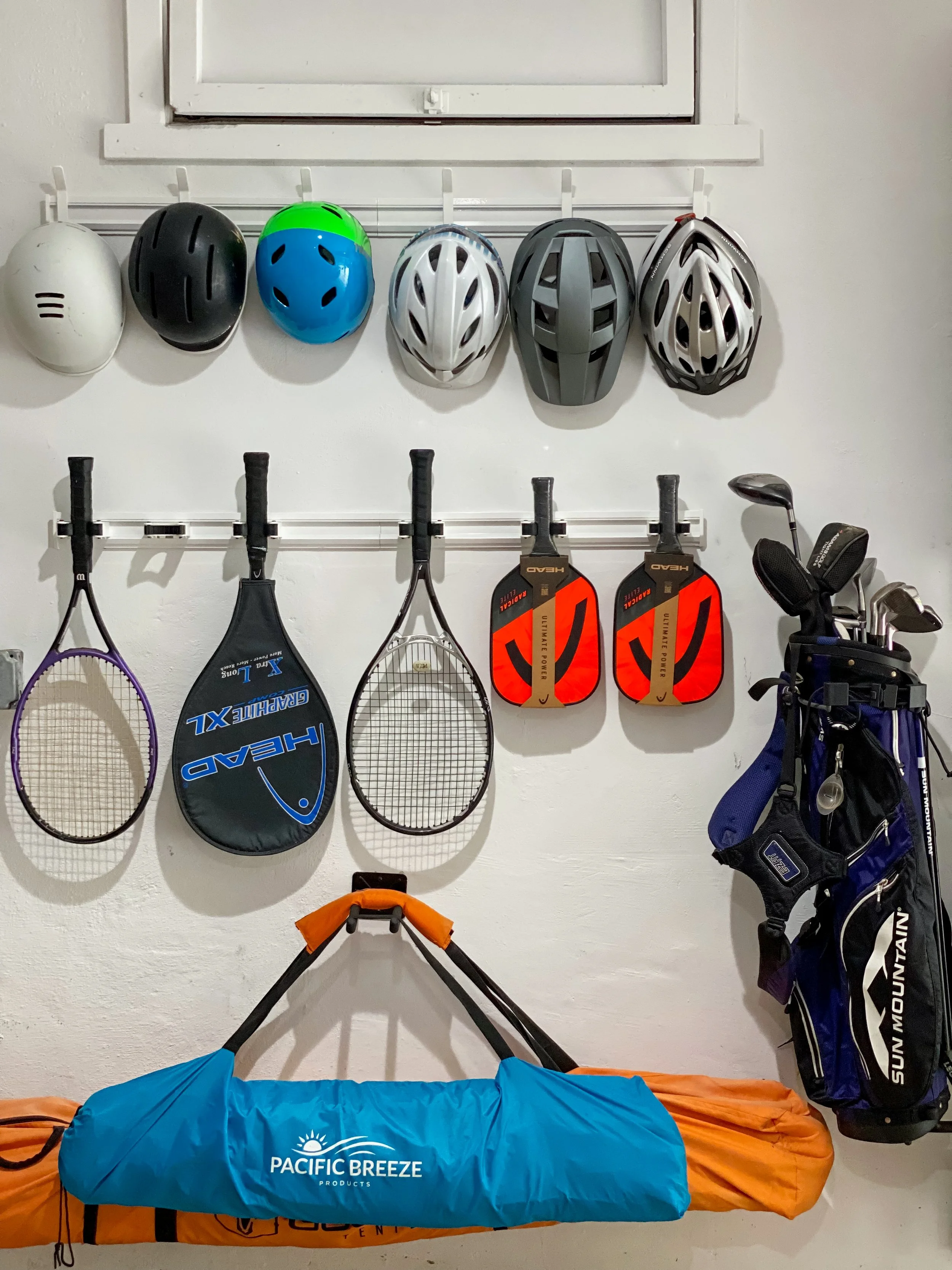 organized tennis rackets and helmets hang on a wall