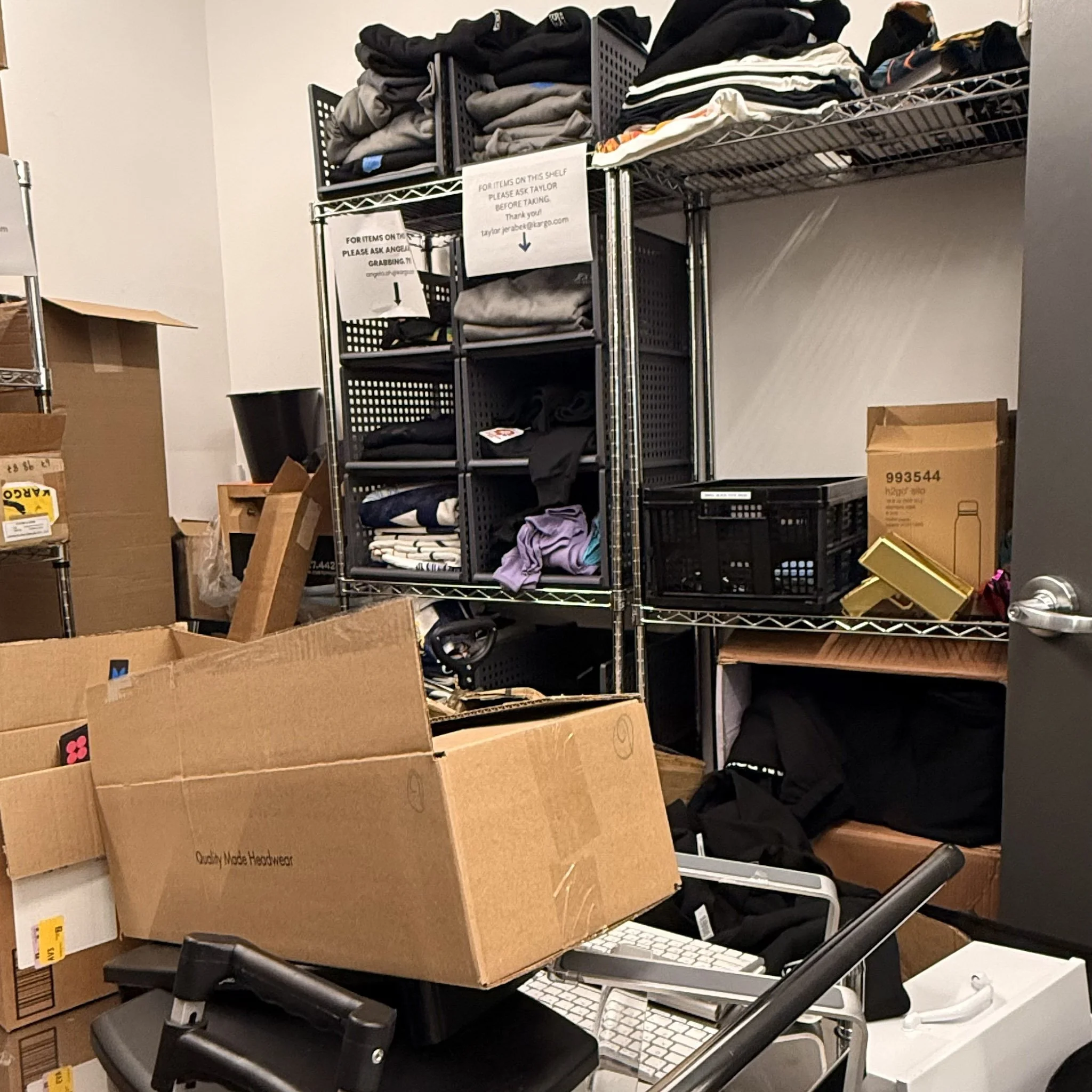 Metal shelving unit filled with folded clothes and boxes in a storage room.