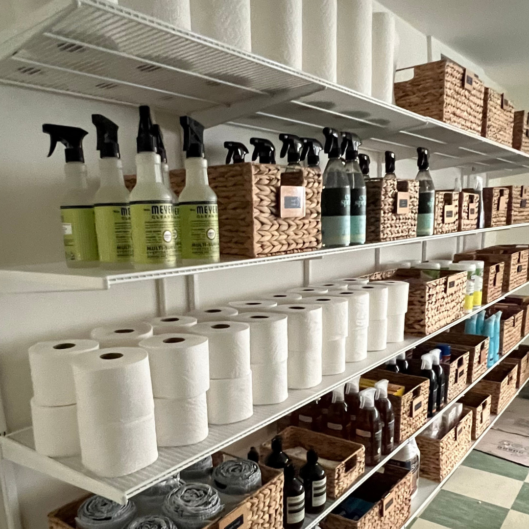 Shelves filled with cleaning supplies, paper towels, and storage baskets in a storage room.