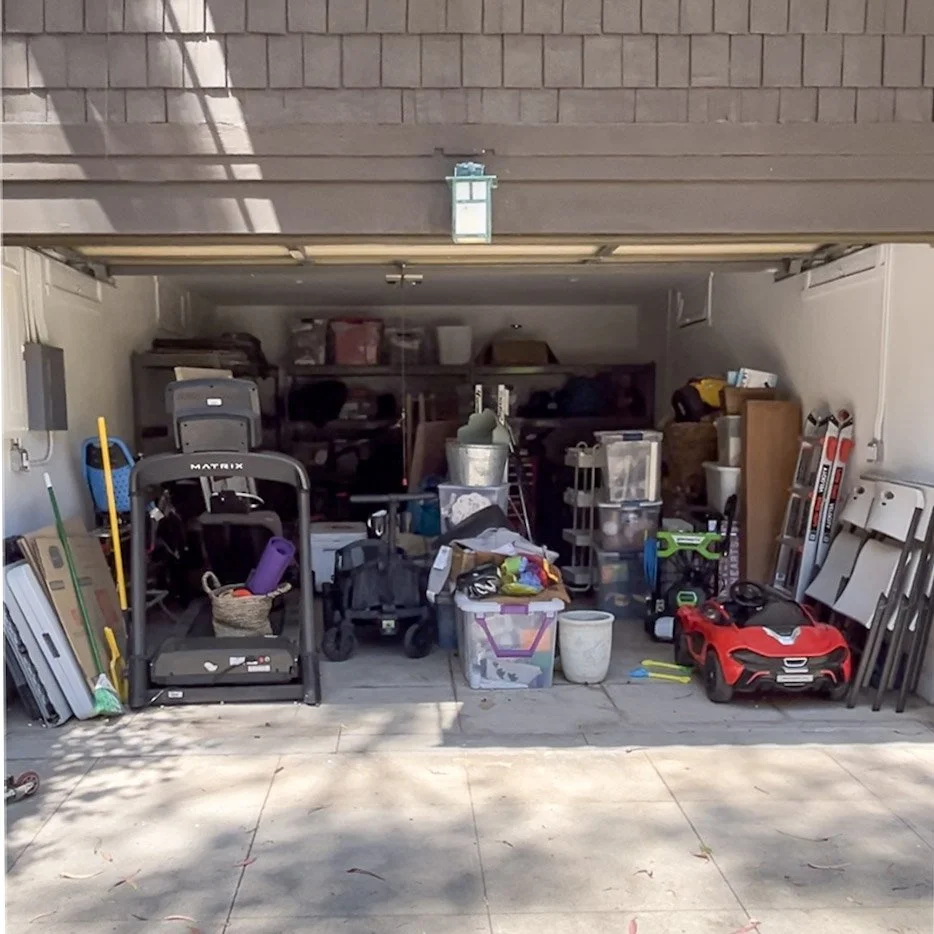A cluttered garage filled with storage bins, children's toys, tools, and various household items.