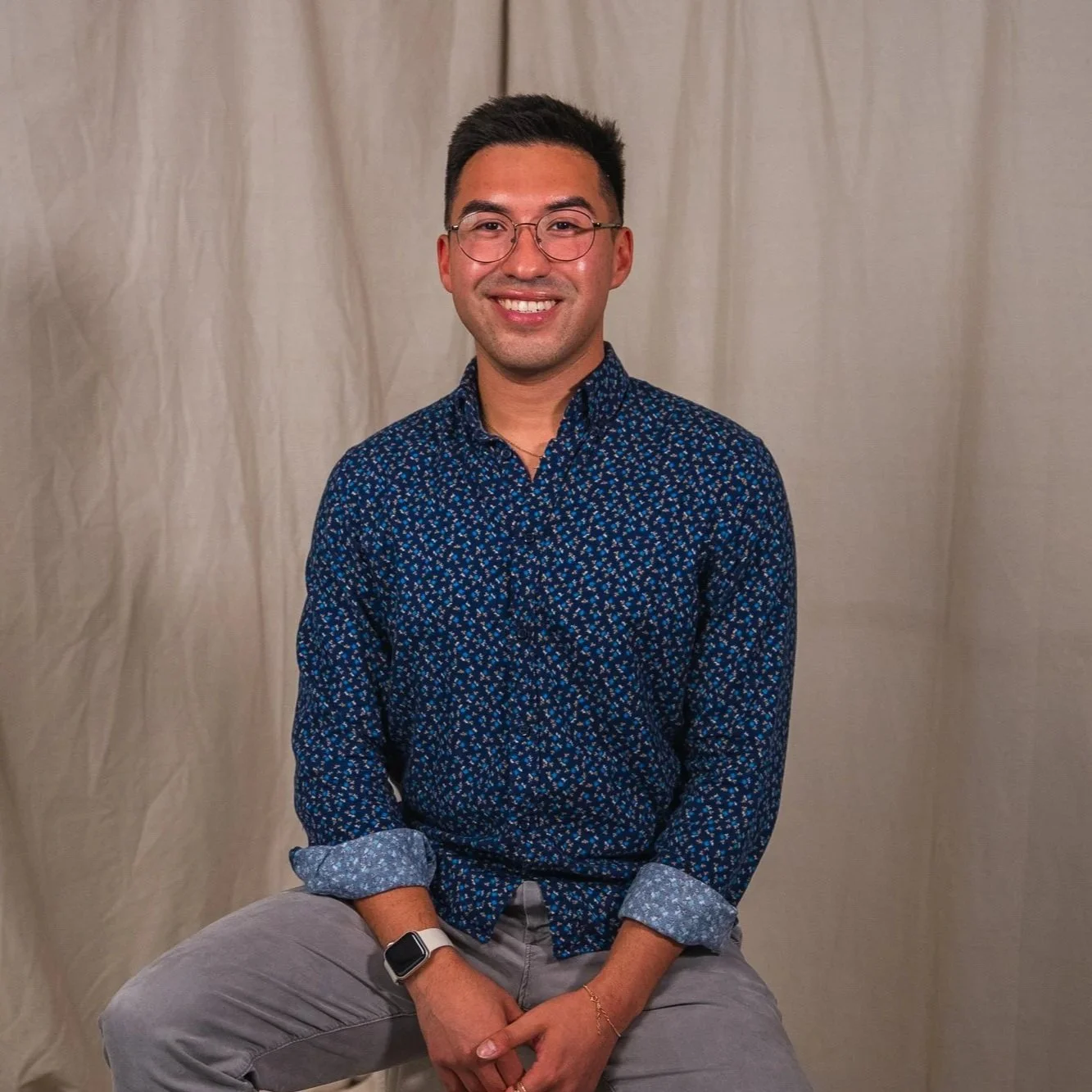 photo of a man in a blue floral button up shirt, posing for a professional headshot