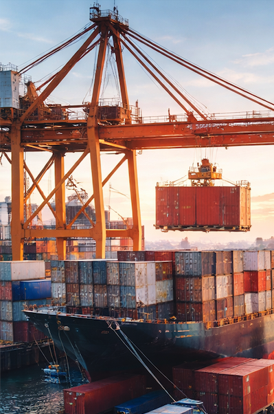 Cargo ship at a busy port, with stacked containers and a large yellow crane lifting a container.