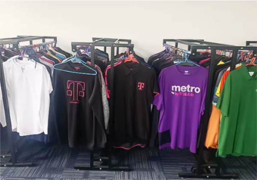 Clothing racks filled with various sports and casual shirts, including T-shirts and jackets, in a retail store.