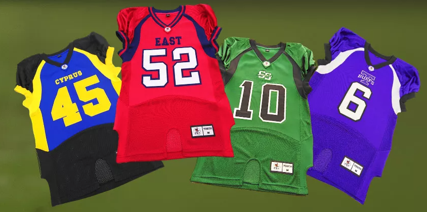Four colorful youth football jerseys on a green background, from left to right: black and yellow with the number 45 and CYPRUS, red with the number 52 and EAST, green with the number 10 and SS, purple with the number 6 and BUCS.