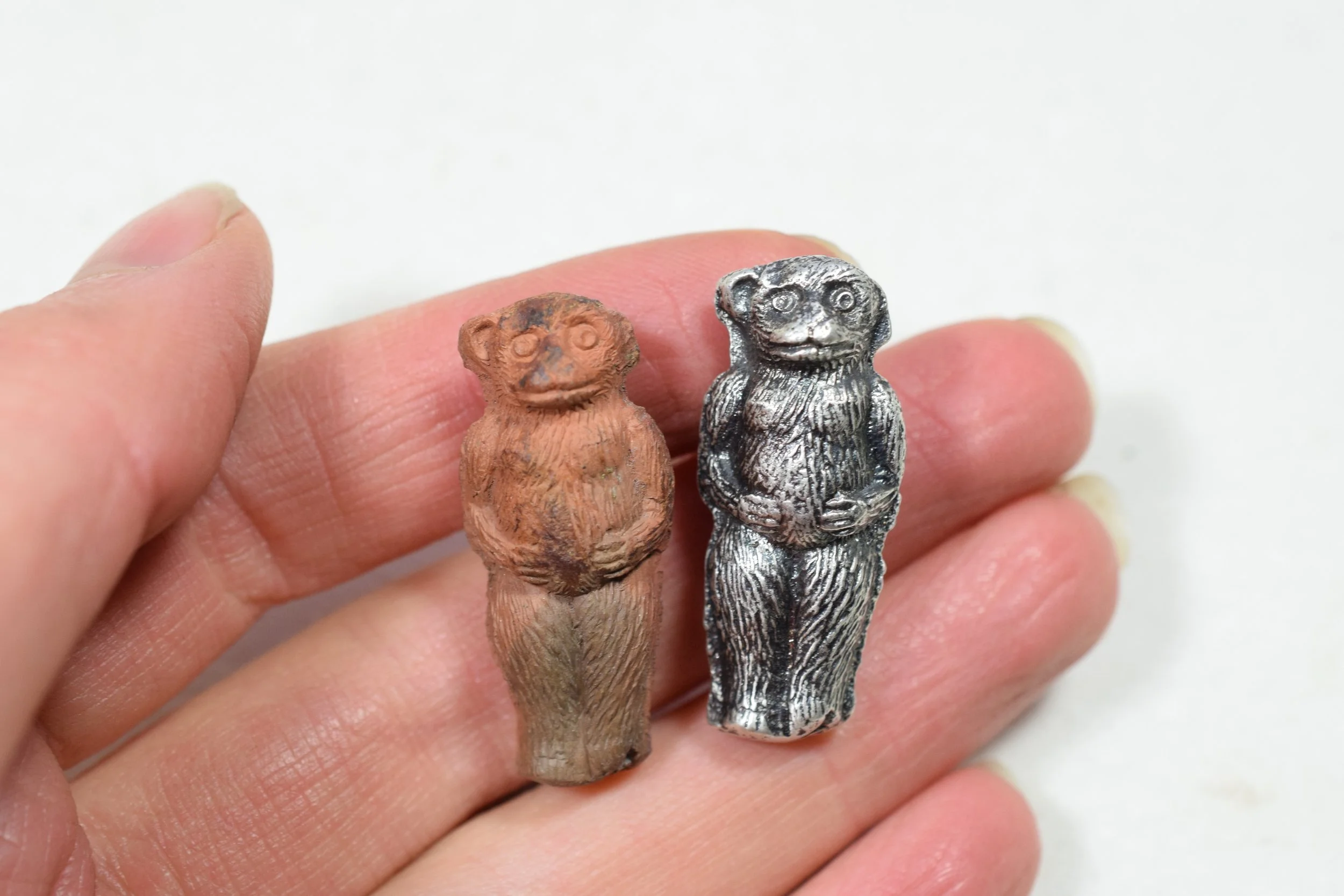 Side-by-side of a silver casting of an Edwardian clay bear toy. 
