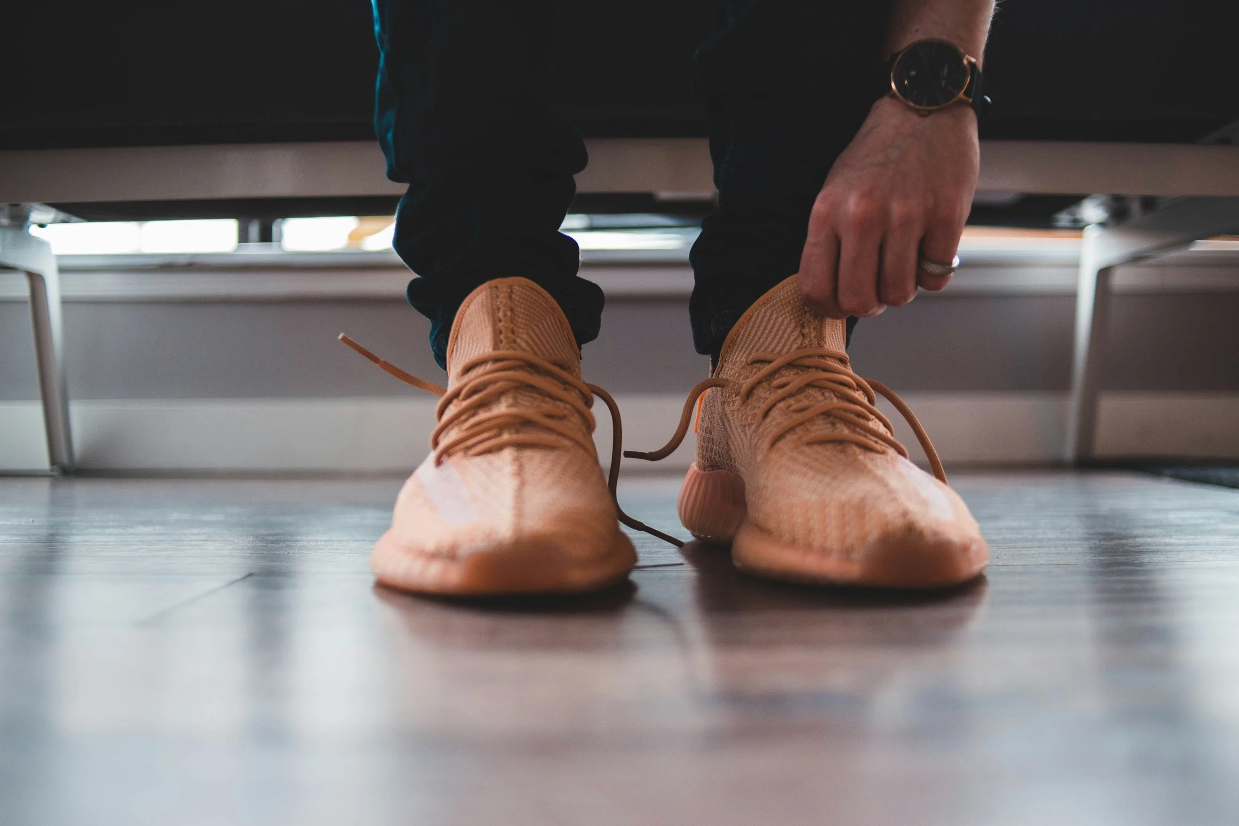 Person wearing grey sneakers while sitting outdoors, representing the transition from work to personal time and the importance of a sustainable work–rest rhythm.