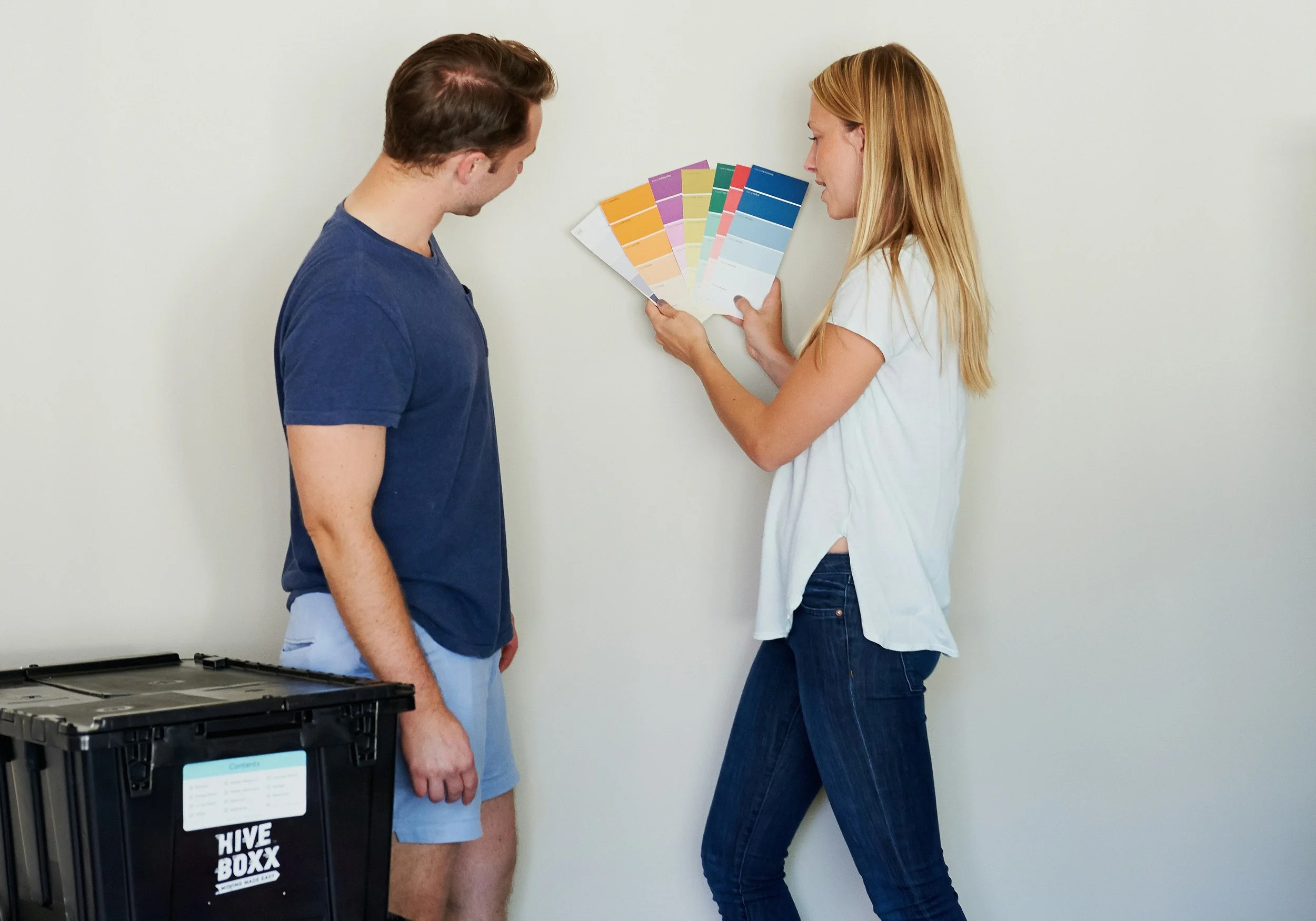 Couple with paint colour swatches spread out while choosing a new living room colour
