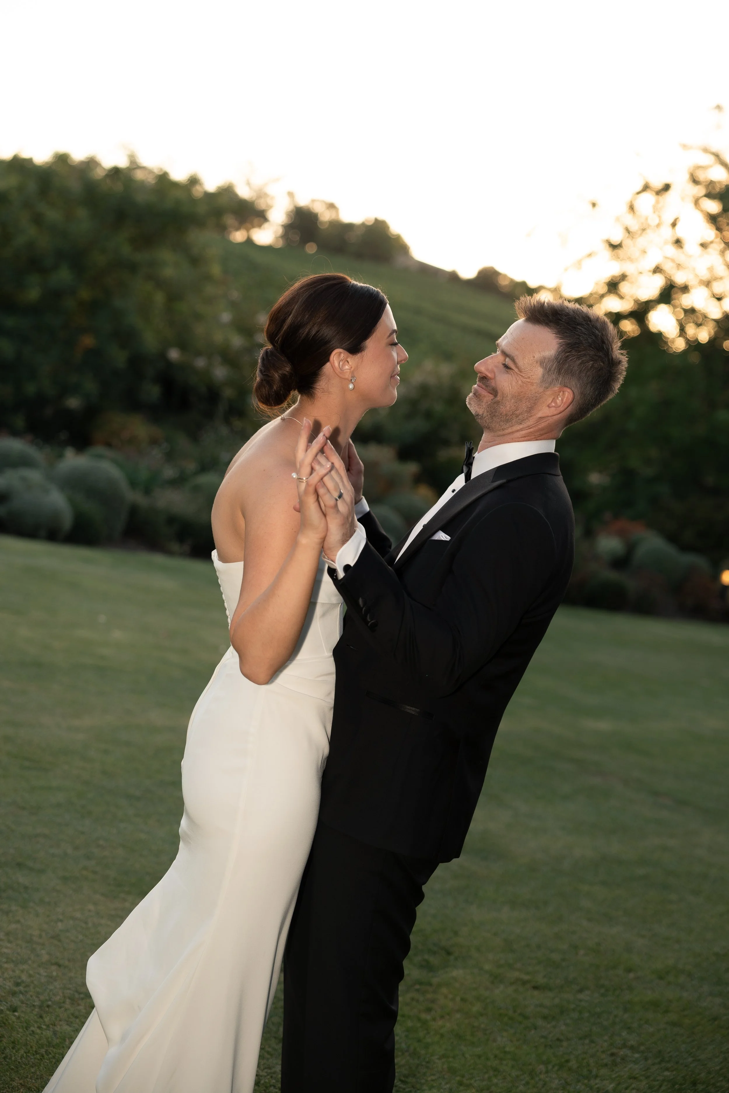 Bride and groom dancing outdoors during sunset.