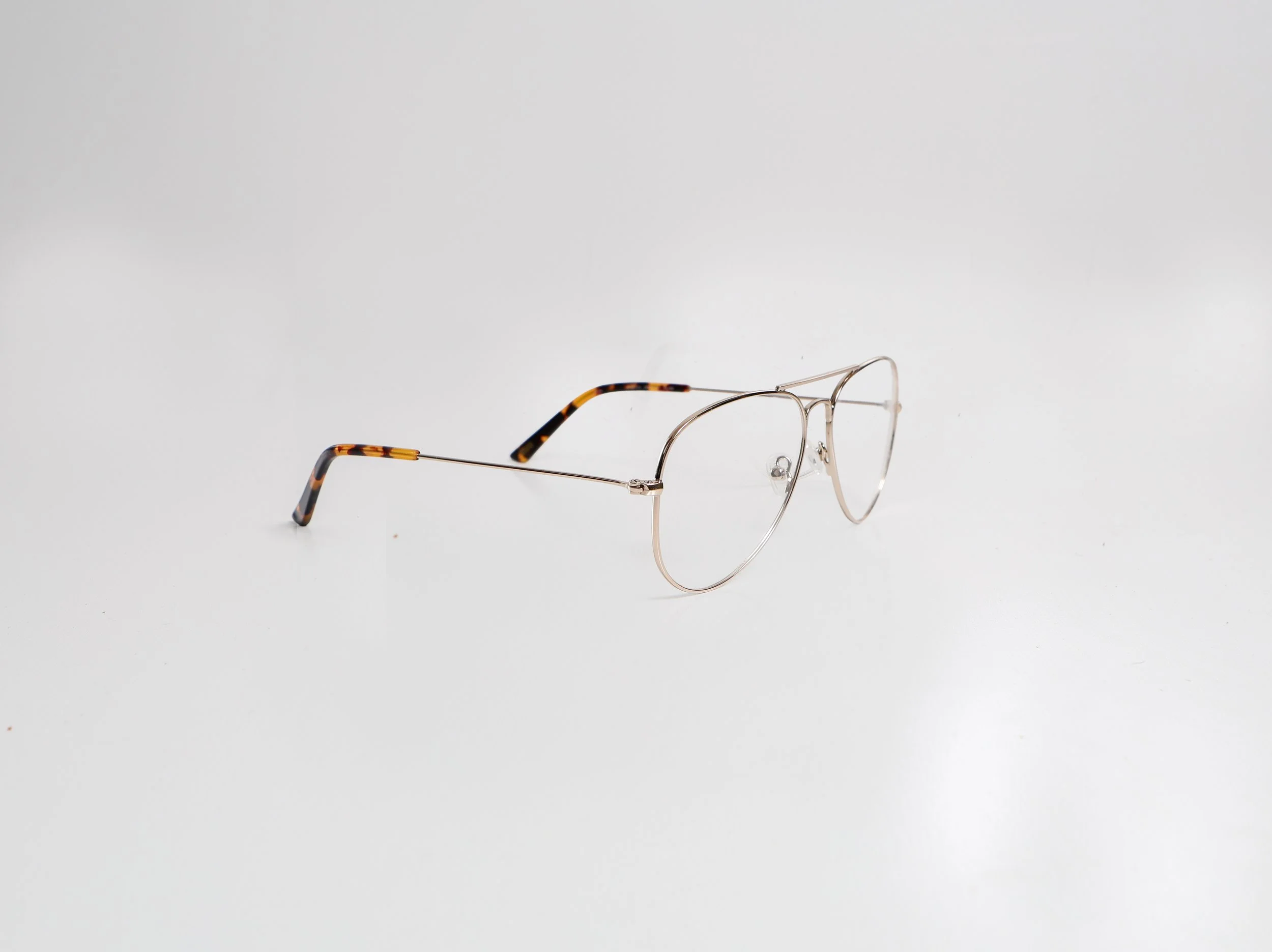A pair of metal-framed eyeglasses with tortoiseshell-patterned temple tips on a plain white surface.
