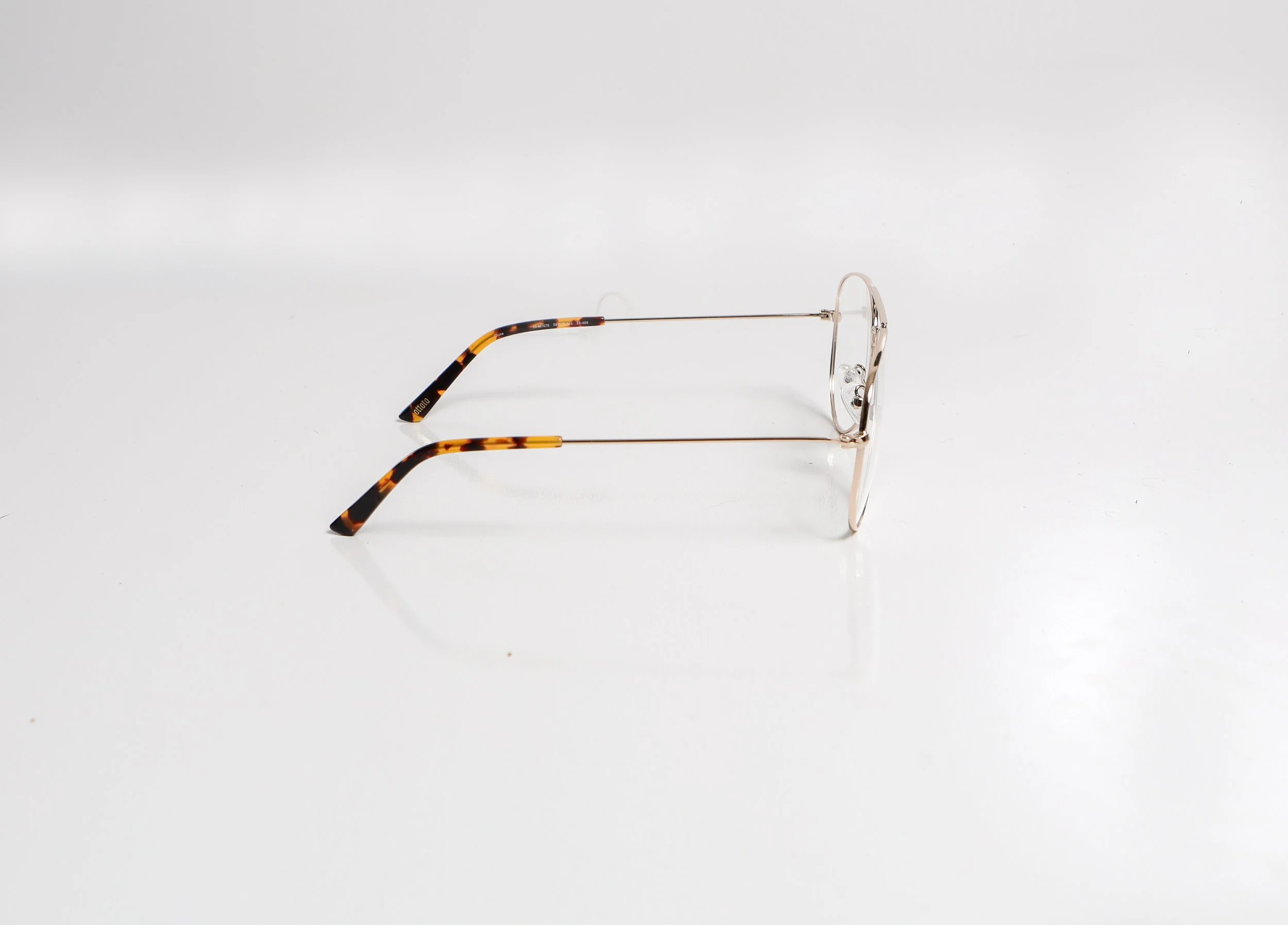 A pair of tortoiseshell-patterned eyeglasses with thin metal frames resting on a white surface.