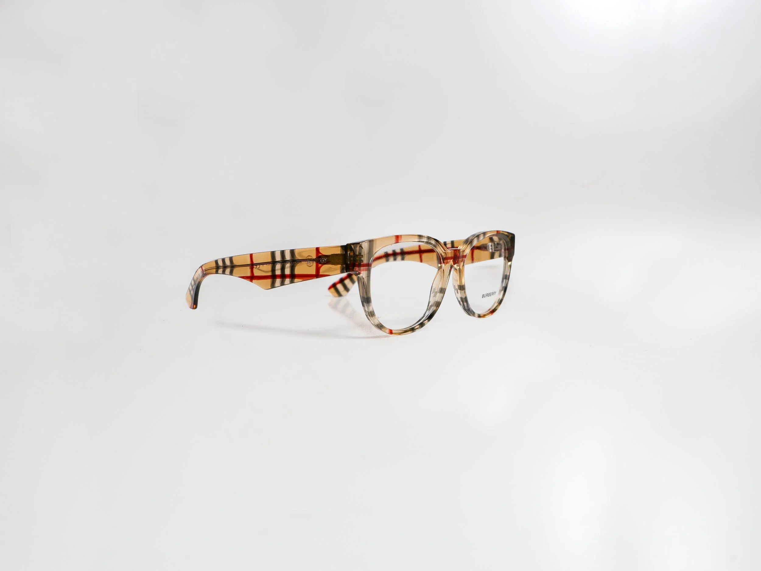 Brown tortoiseshell eyeglasses with a check pattern on a white surface