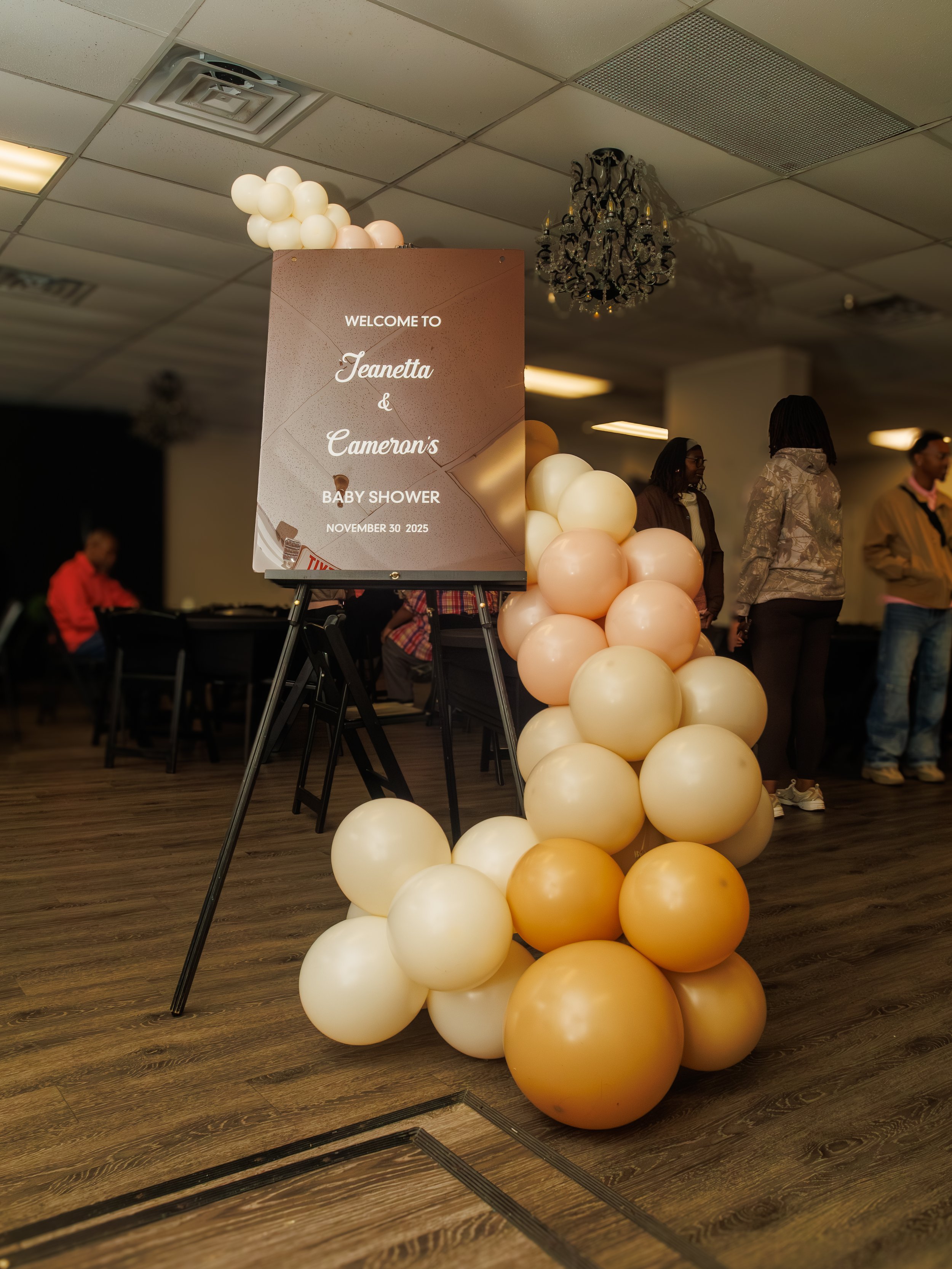 Decorative balloons and a sign announcing a baby shower for Jeanetta and Cameron on November 30, 2025.