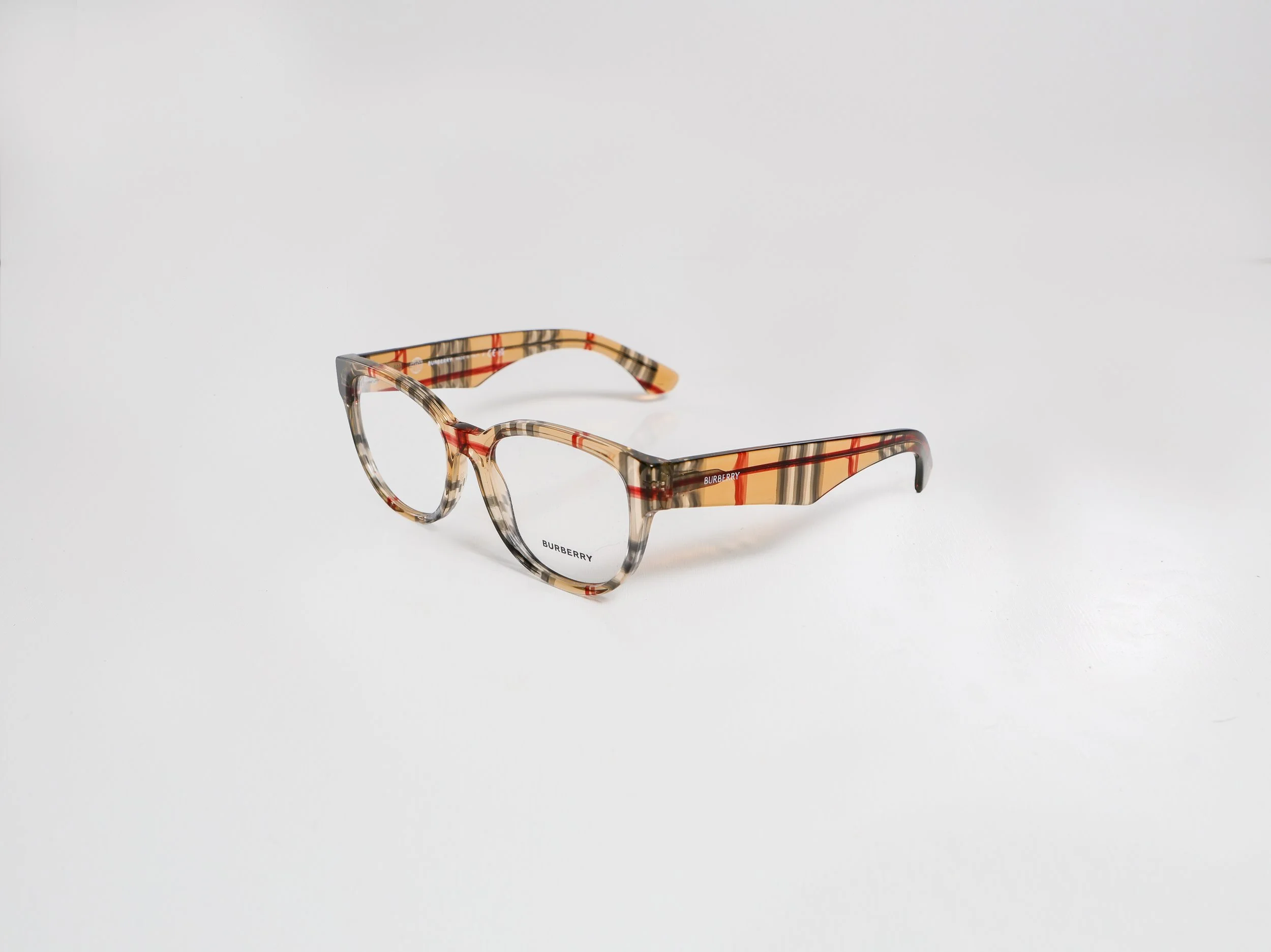 Burberry eyeglasses with a beige, black, and red plaid pattern frame, placed on a white background