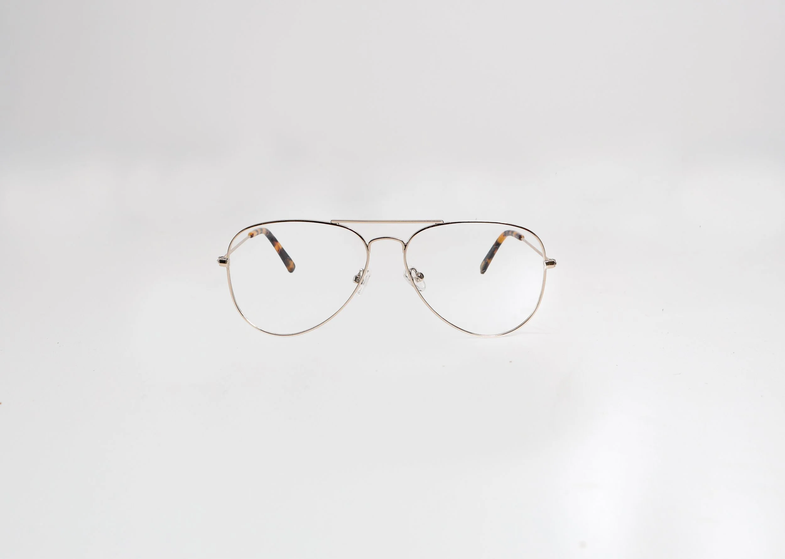 A pair of silver aviator-style eyeglasses with tortoiseshell tips on the temples, placed on a plain white background.