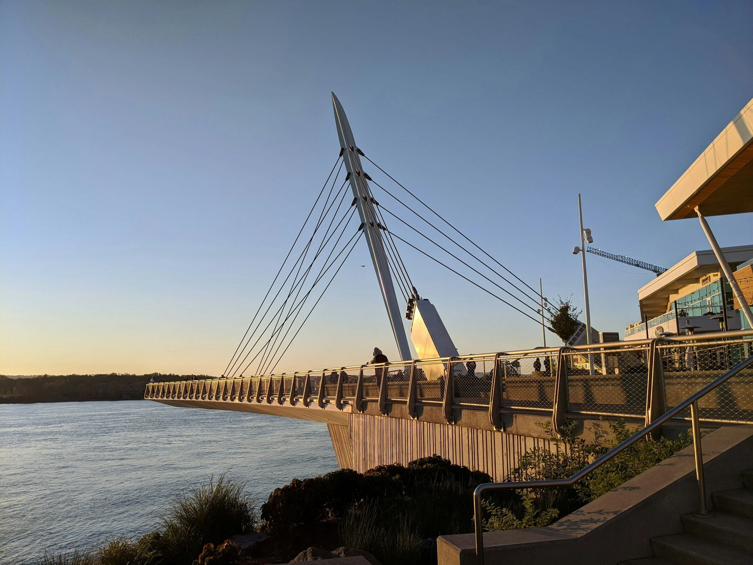 A modern pedestrian bridge over a body of water at sunset on the Vancouver, WA waterfront.