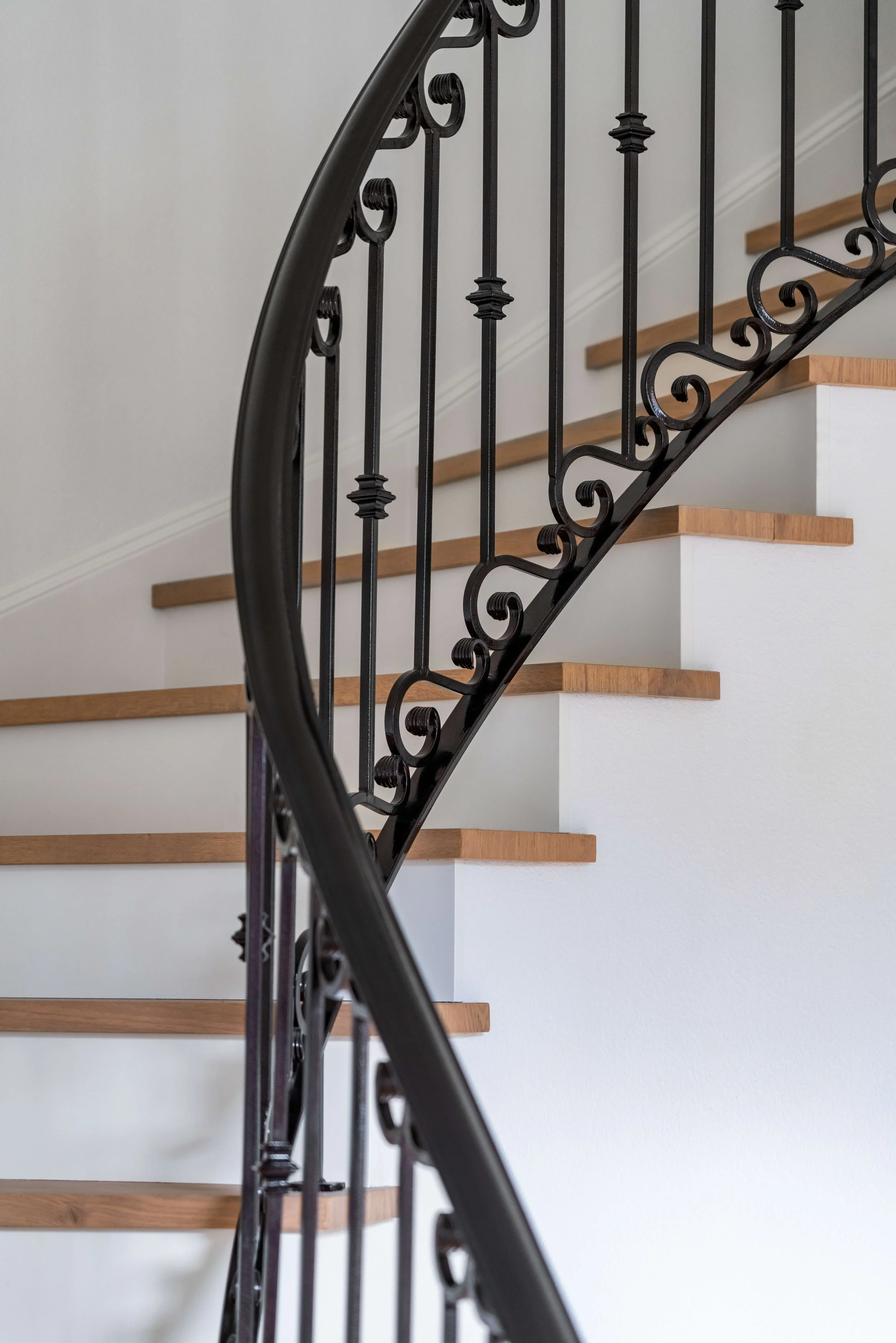 Interior staircase with black wrought-iron railing and wooden steps.